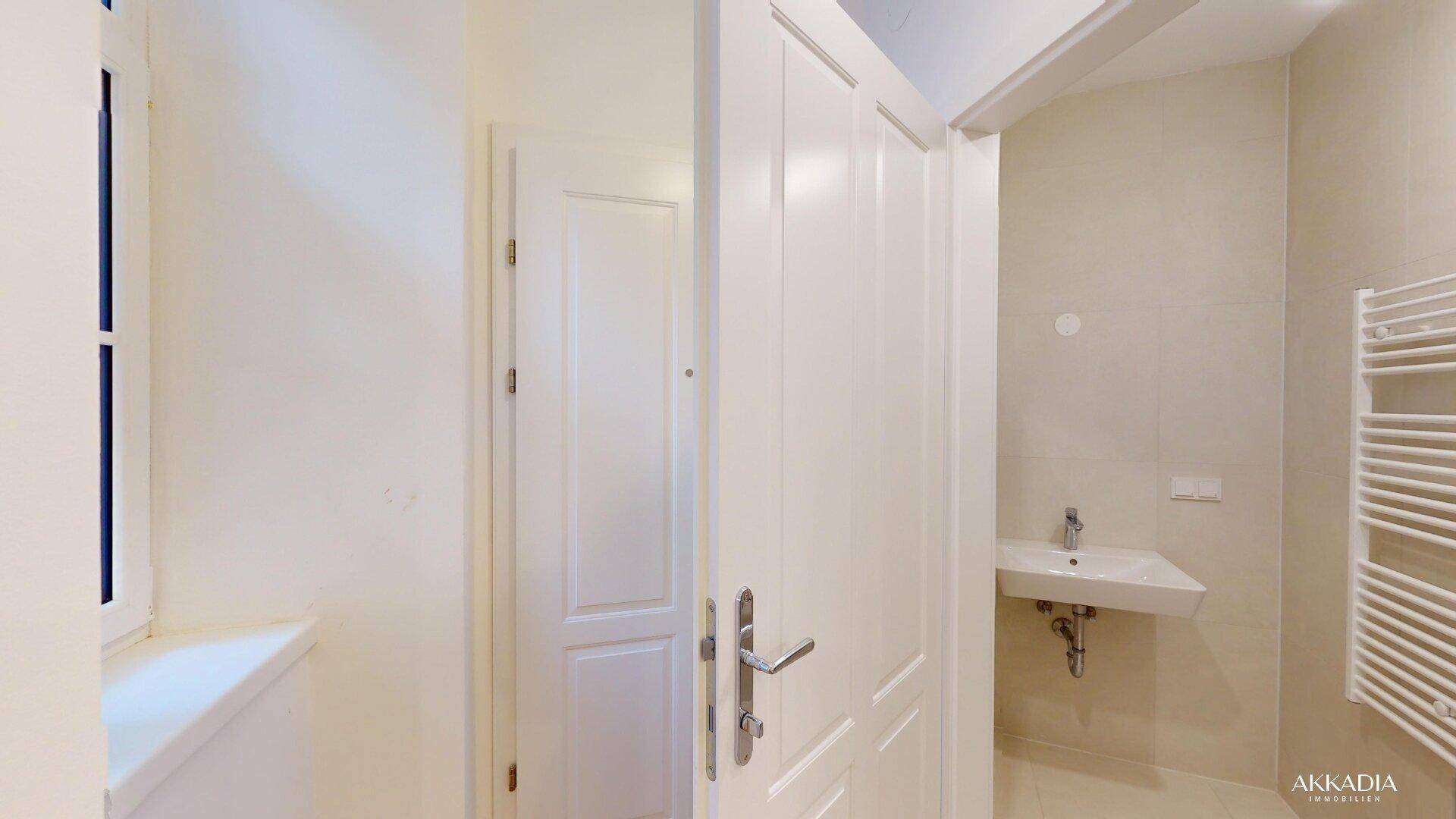 Helles Badezimmer mit Fenster, modernem Waschbecken und beheiztem Handtuchhalter.