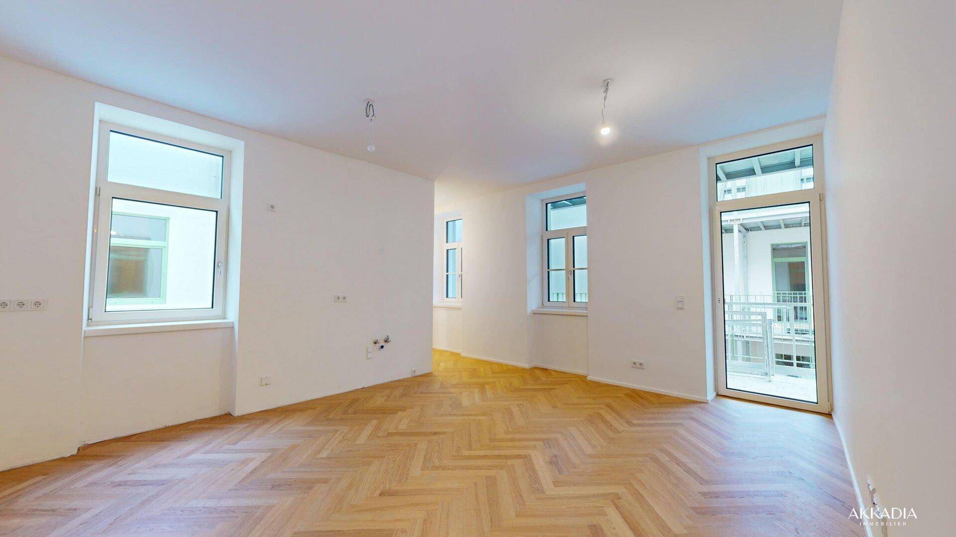 Geräumiges, helles Zimmer mit Fischgrätparkett und mehreren Fenstern, bereit zur Einrichtung.