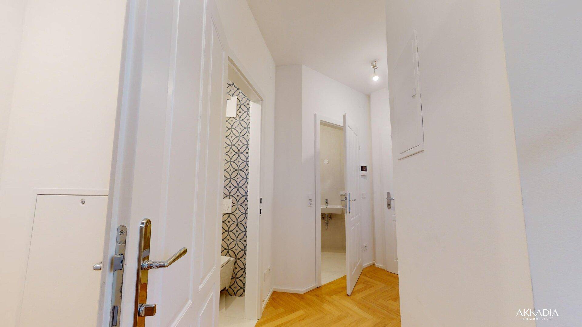 Heller Flur mit Holztüren und Blick auf ein modern gefliestes Badezimmer oder Gäste-WC.
