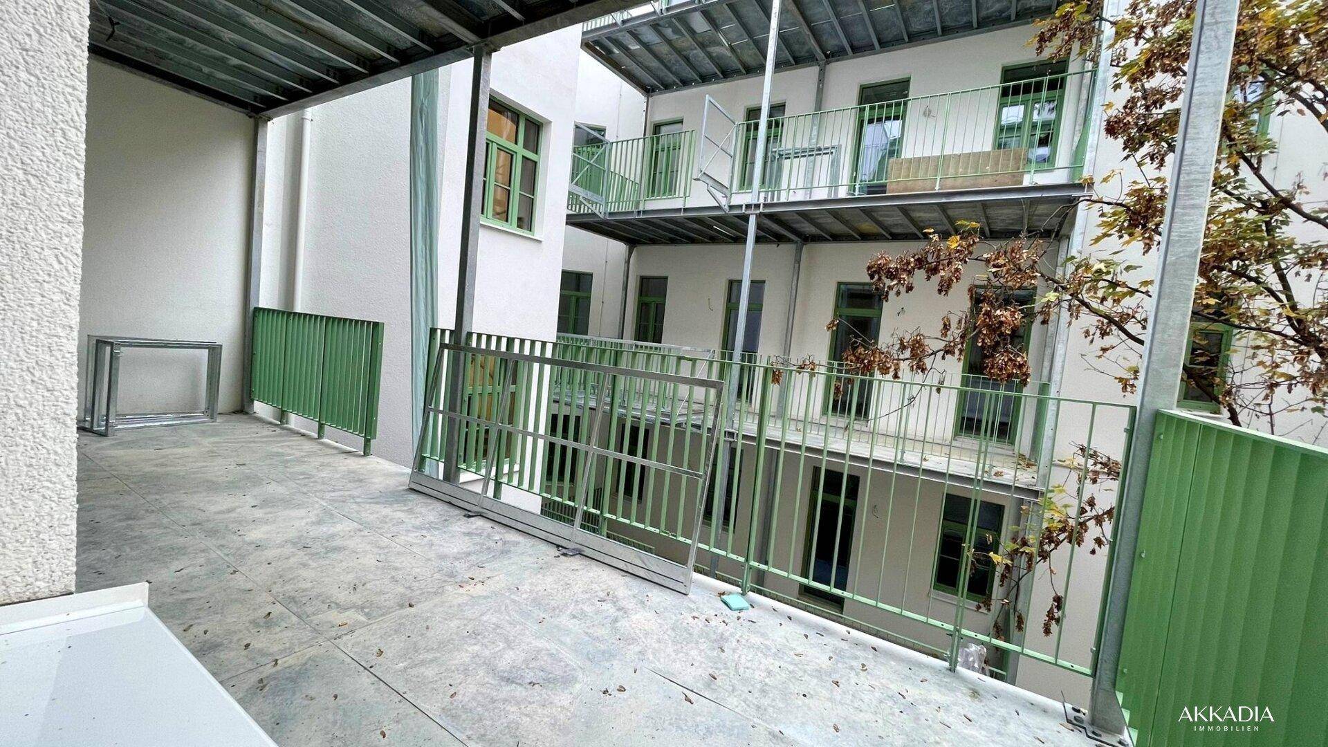 Große Terrasse im Innenhof mit grünen Geländern, die noch fertiggestellt wird.
