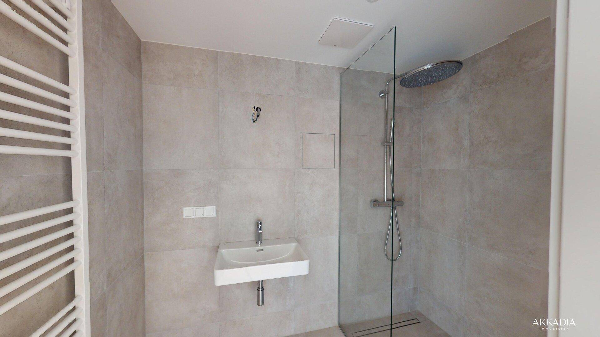 Modernes Badezimmer mit begehbarer Dusche, Regenbrause und beheiztem Handtuchhalter.