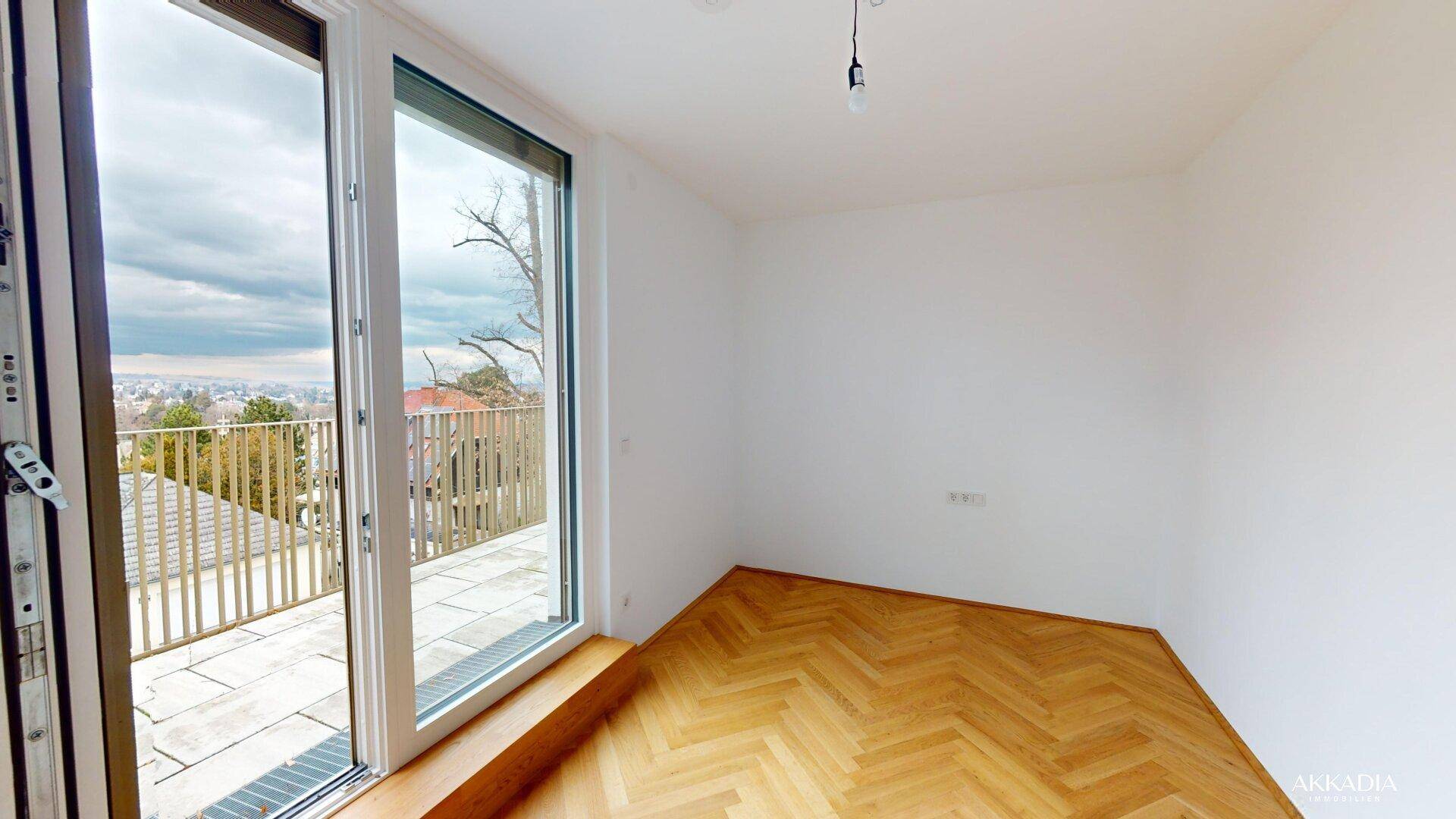 Helles Schlafzimmer mit Fischgrätparkett und direktem Zugang zu einer großen Terrasse.