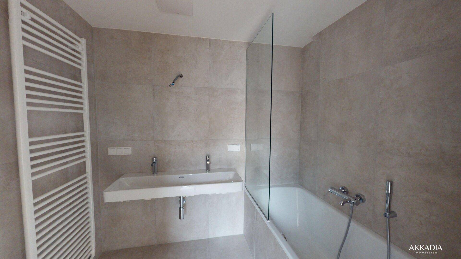 Modernes Badezimmer mit Badewanne, Duschwand aus Glas und beheiztem Handtuchhalter.