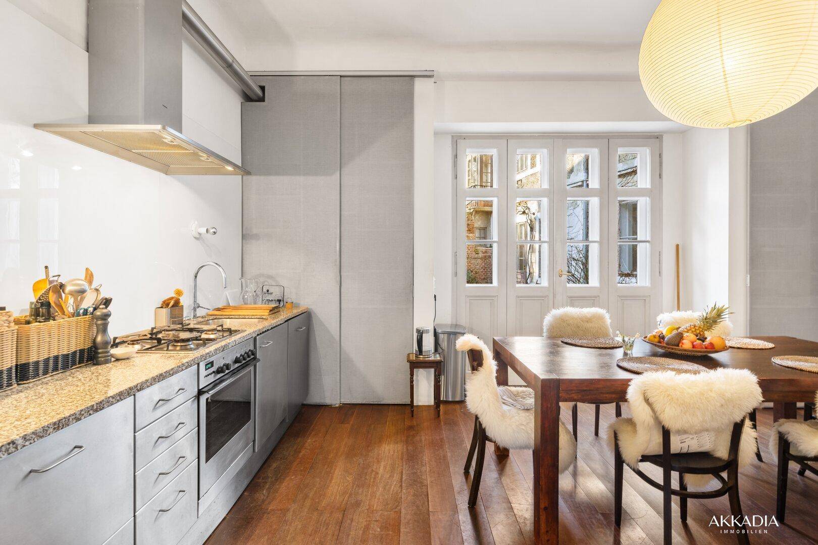 Funktionale Küche mit Granitarbeitsplatte und Essbereich, ausgestattet mit modernen Geräten und Holzboden.