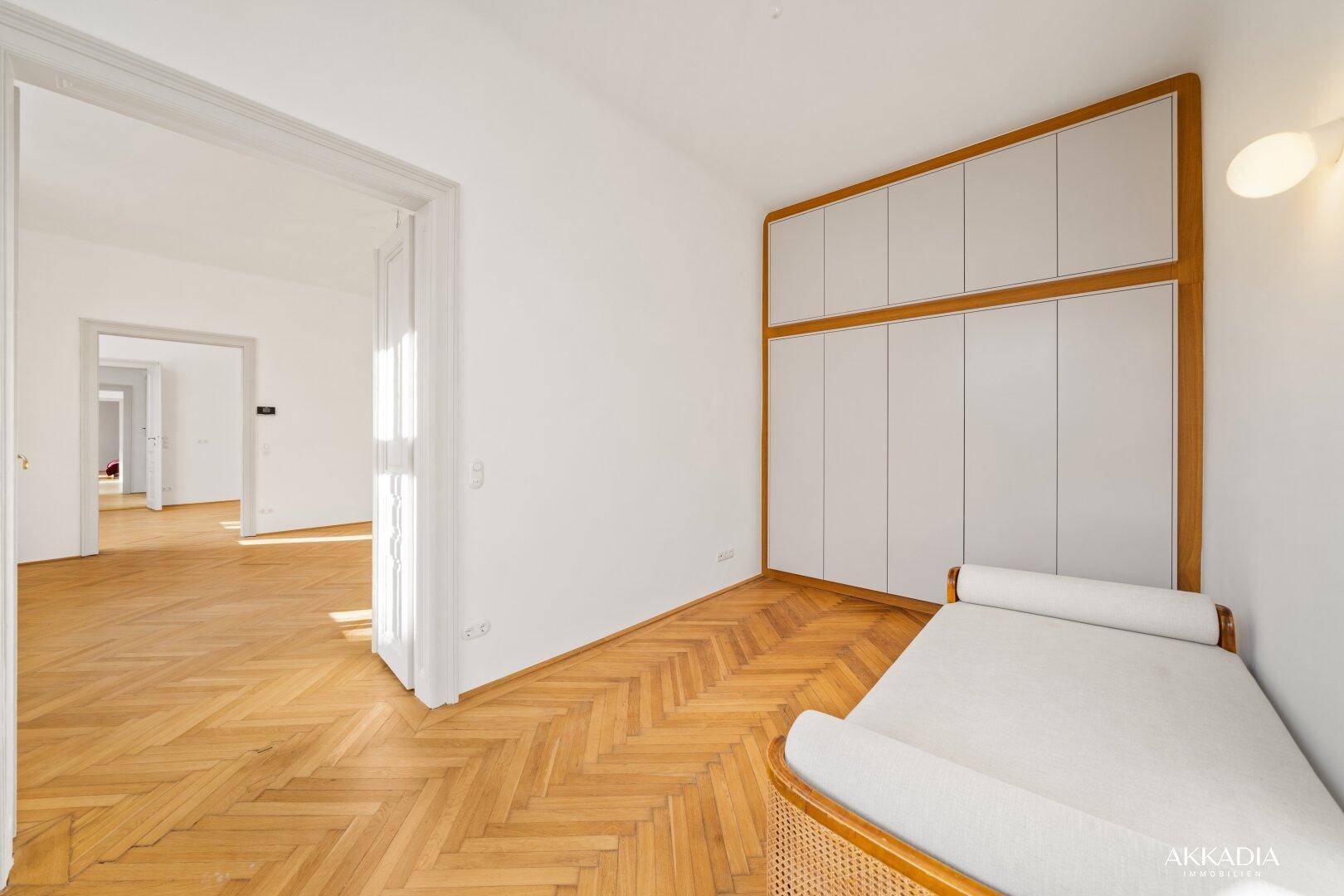 Helles Schlafzimmer mit Fischgrätparkett und einem eleganten Einbauschrank, bereit zur individuellen Gestaltung.