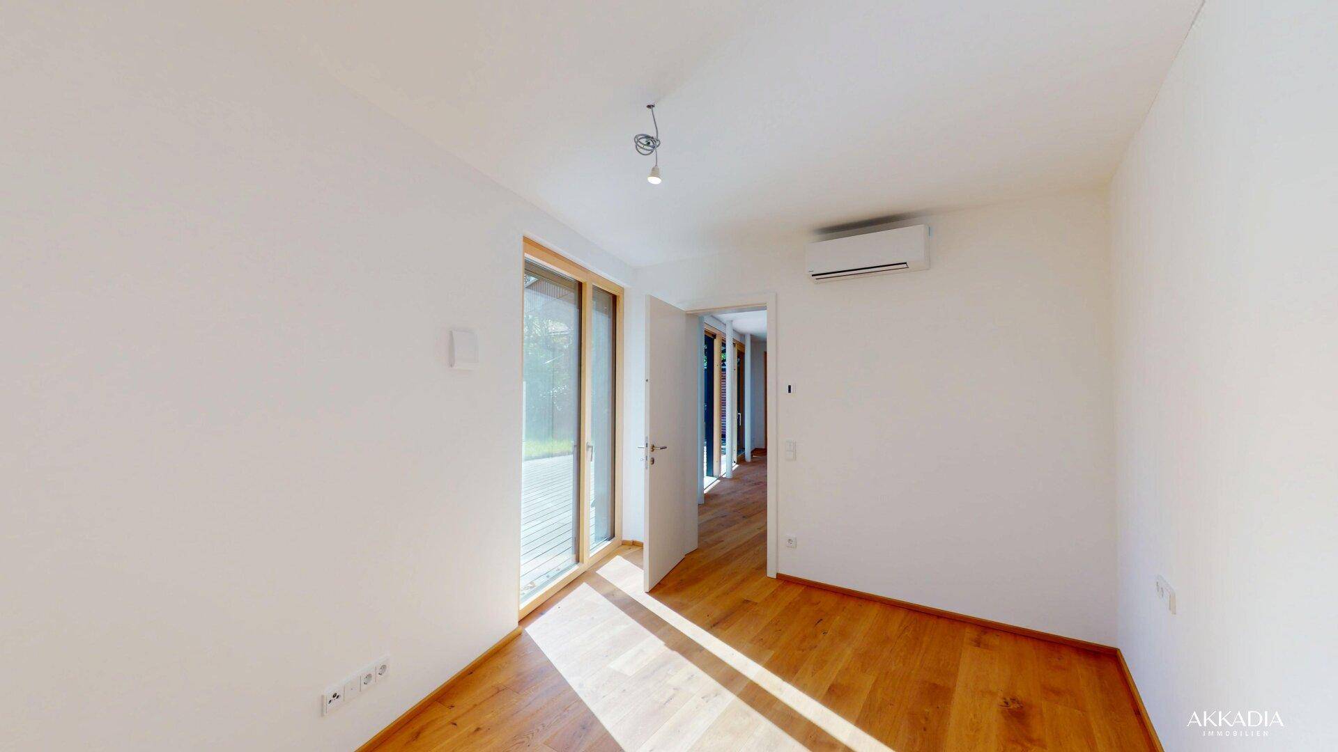 Sonniges Zimmer mit Holzboden und Zugang zum Außenbereich, ideal als Schlaf- oder Arbeitszimmer.