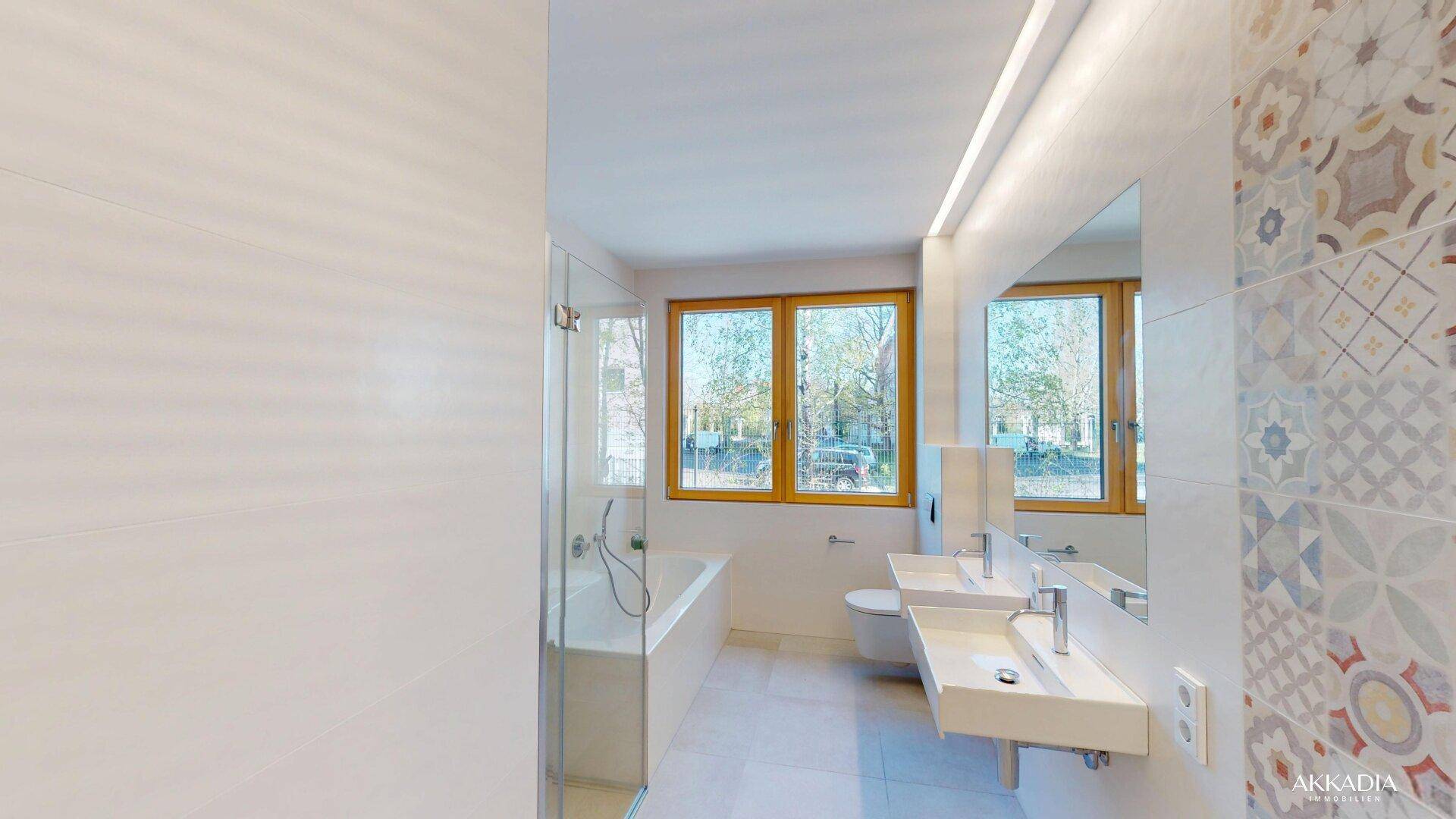Helles Badezimmer mit Badewanne, Doppelwaschbecken, Dusche und Fenster für natürliche Belüftung.