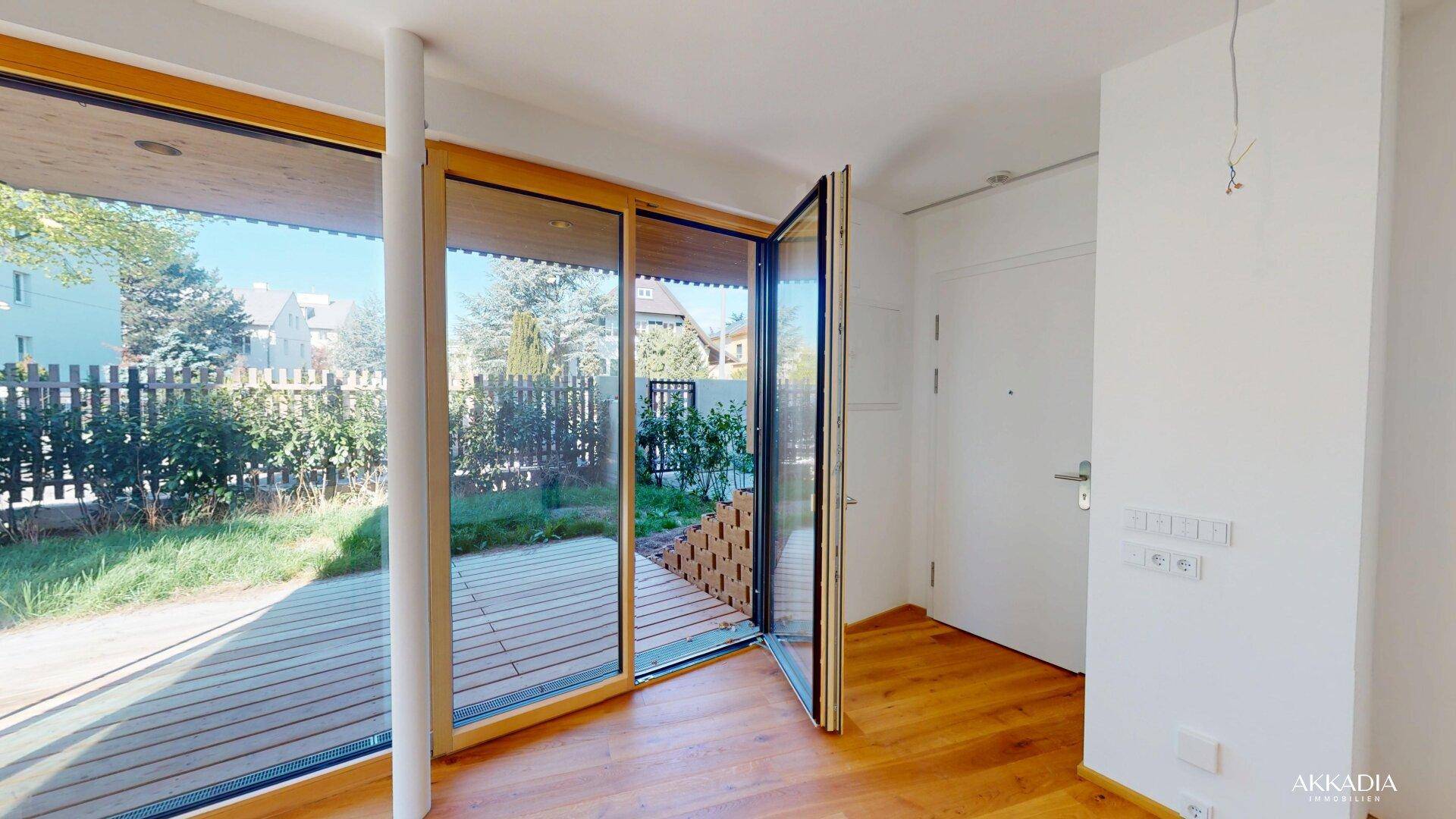 Eingangsbereich mit Holzboden und großen Glasfronten, die direkten Zugang zur Terrasse und zum Garten bieten.