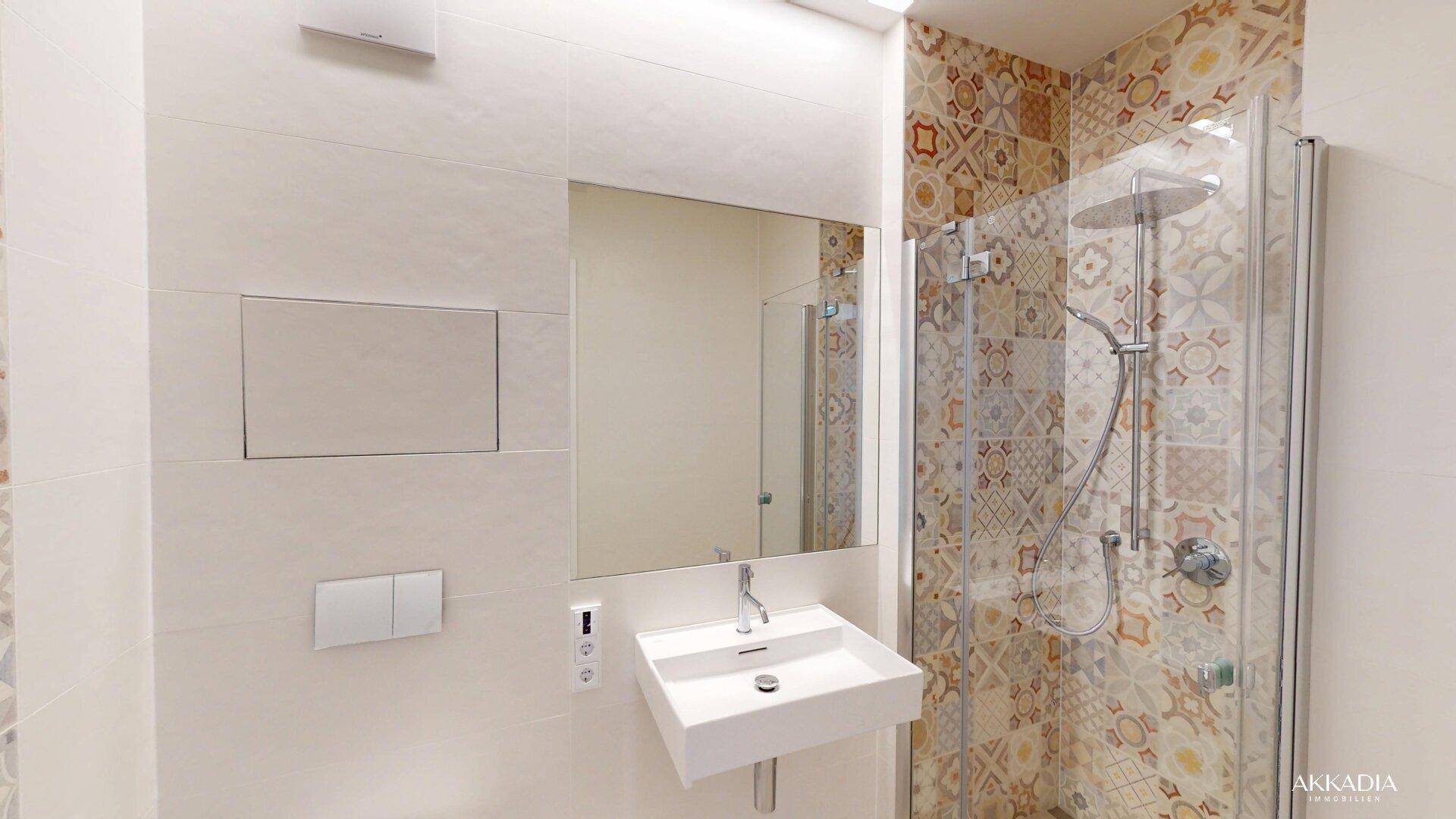 Modernes Badezimmer mit gemusterten Fliesen, bodengleicher Dusche und elegantem Waschbecken.