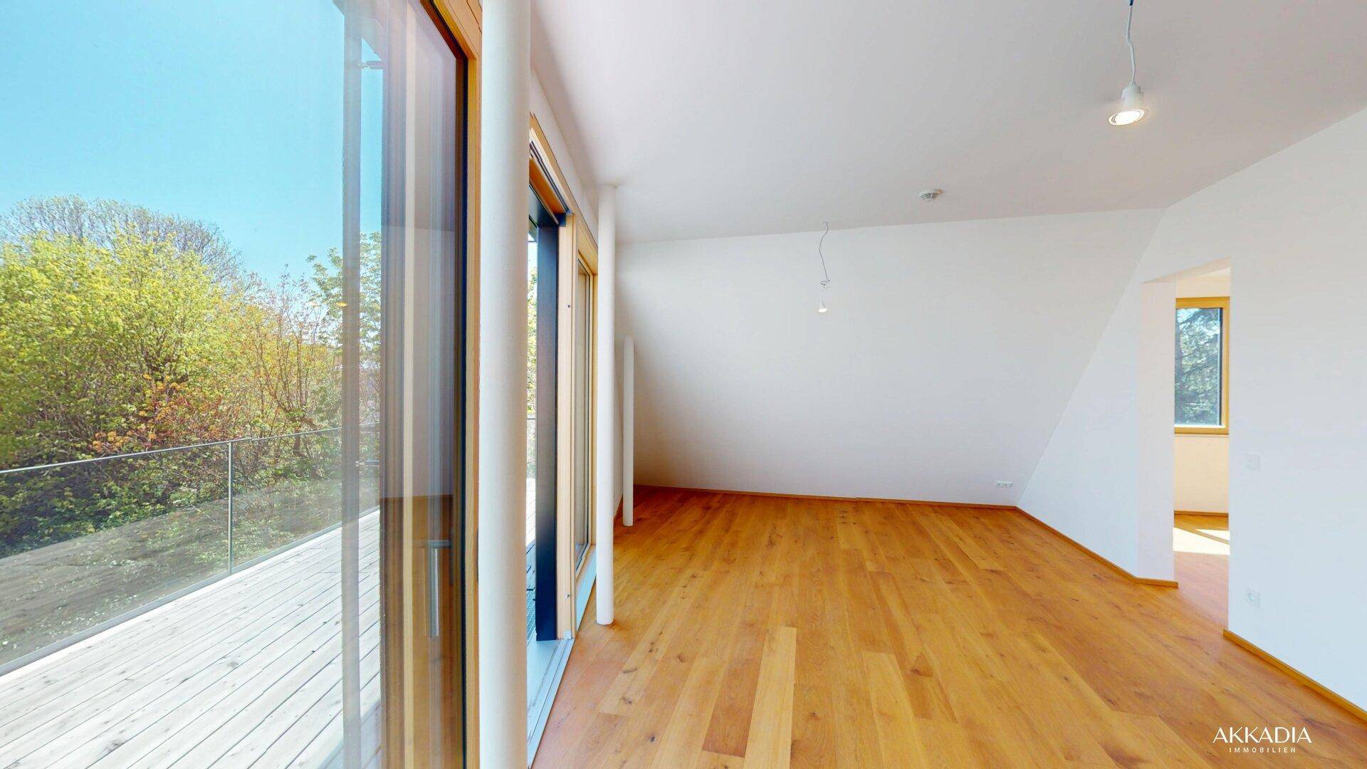 Geräumiger Wohnraum mit Holzboden, großen Fenstern und Zugang zur Terrasse.