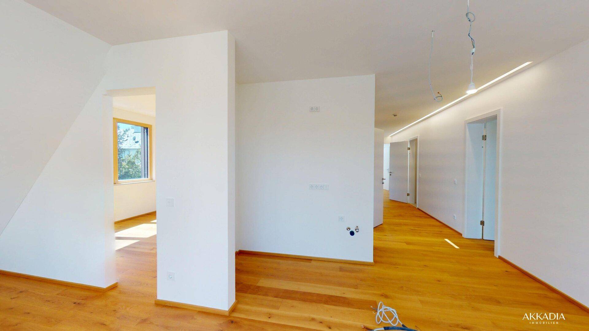 Heller Flurbereich mit Holzboden, weißen Wänden und integrierter Deckenbeleuchtung.