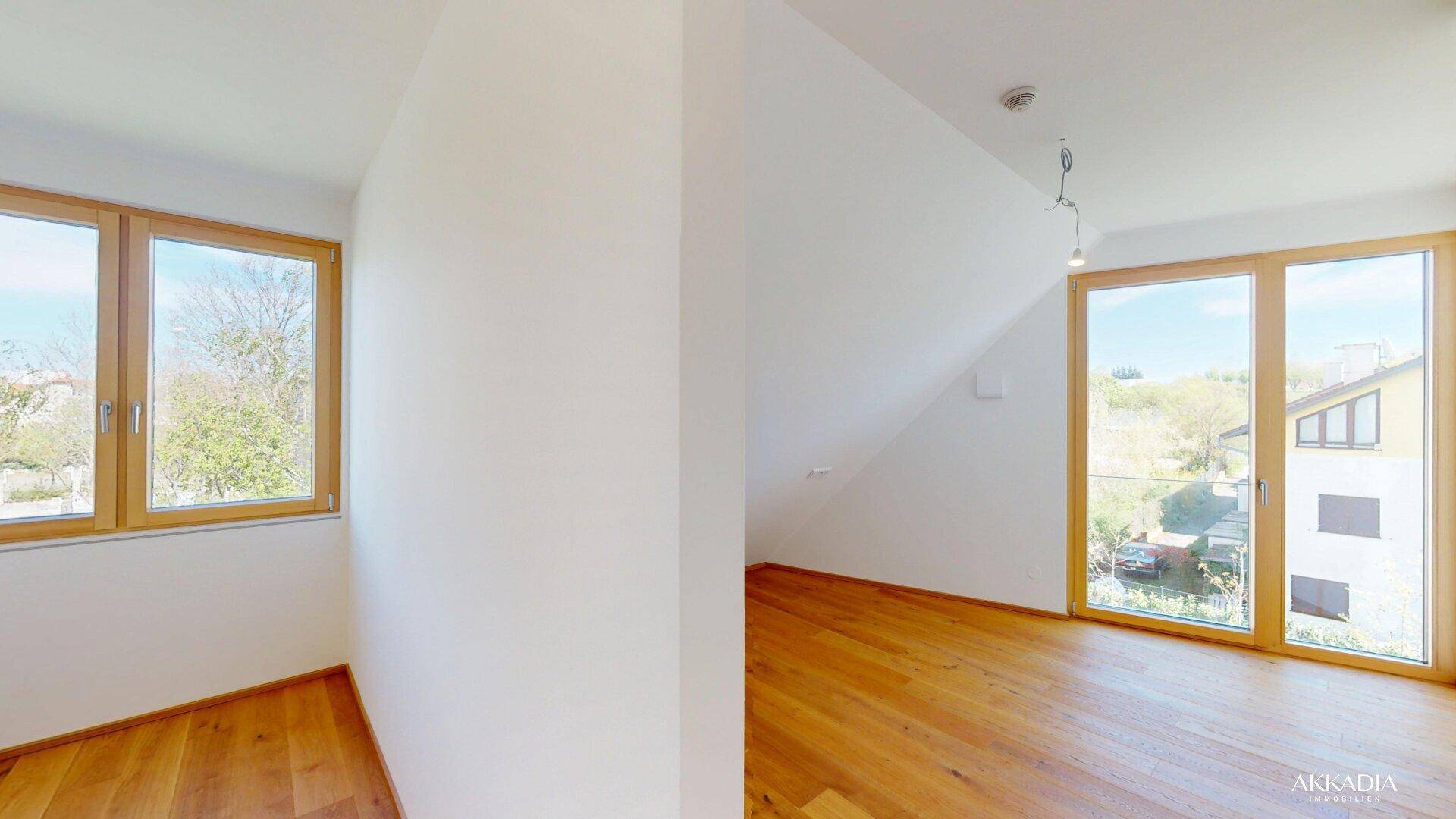 Heller Raum mit Holzboden, weißen Wänden und zwei Fenstern, ideal als Schlafzimmer.