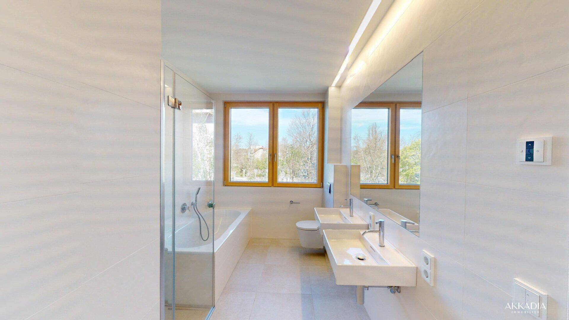 Helles, modernes Badezimmer mit Badewanne, Dusche, Doppelwaschbecken und Fenster.