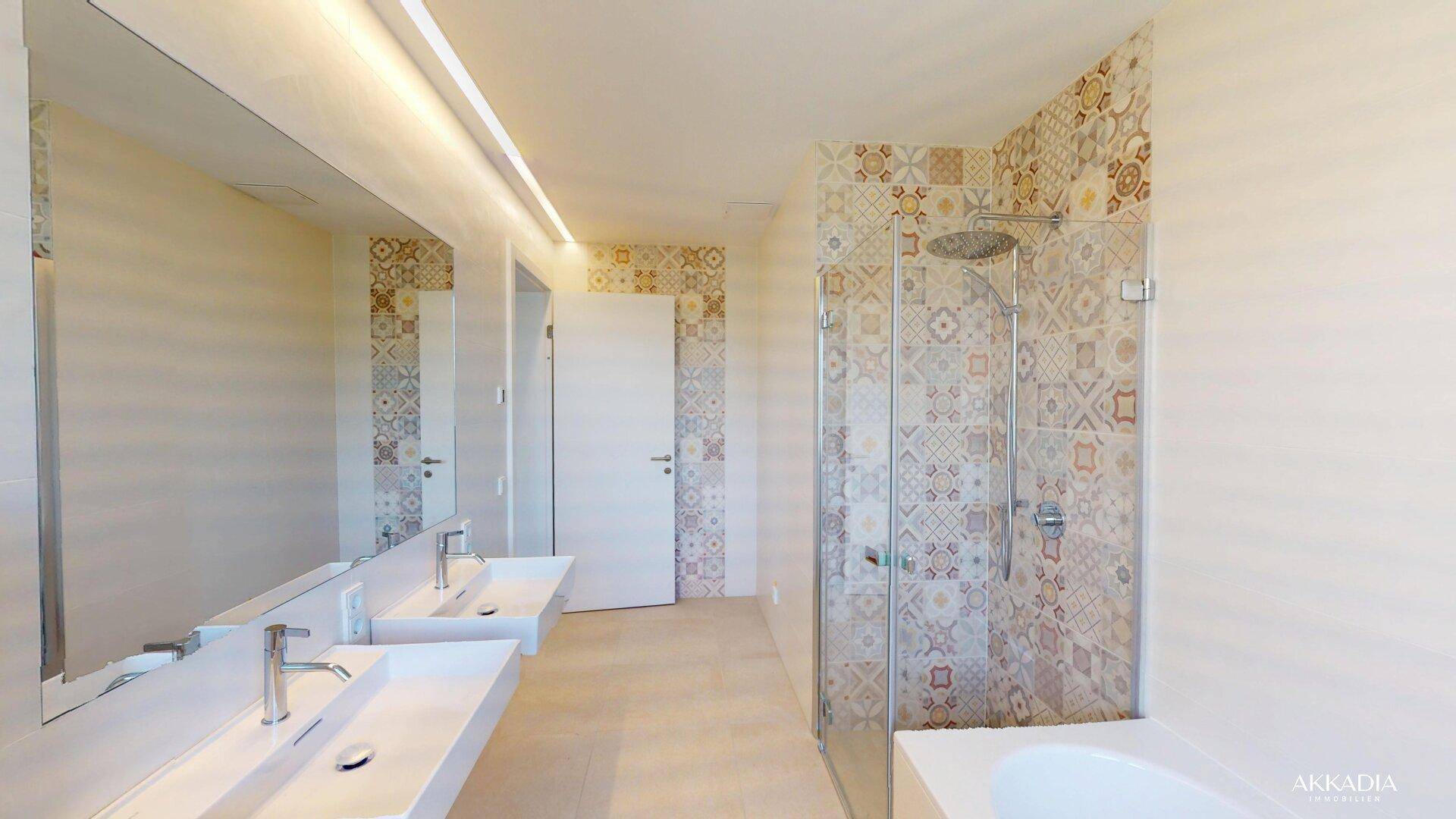Modernes Badezimmer mit gemusterten Fliesen, Doppelwaschbecken und Badewanne.