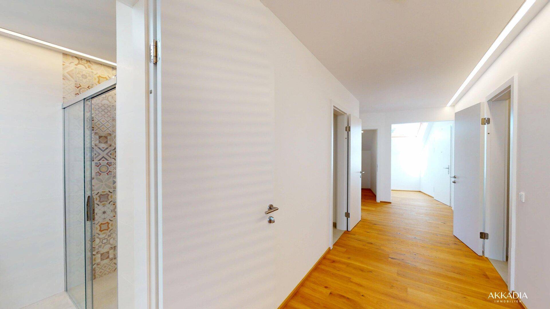 Heller Flur mit Holzboden, weißen Wänden und angrenzendem Duschbereich.