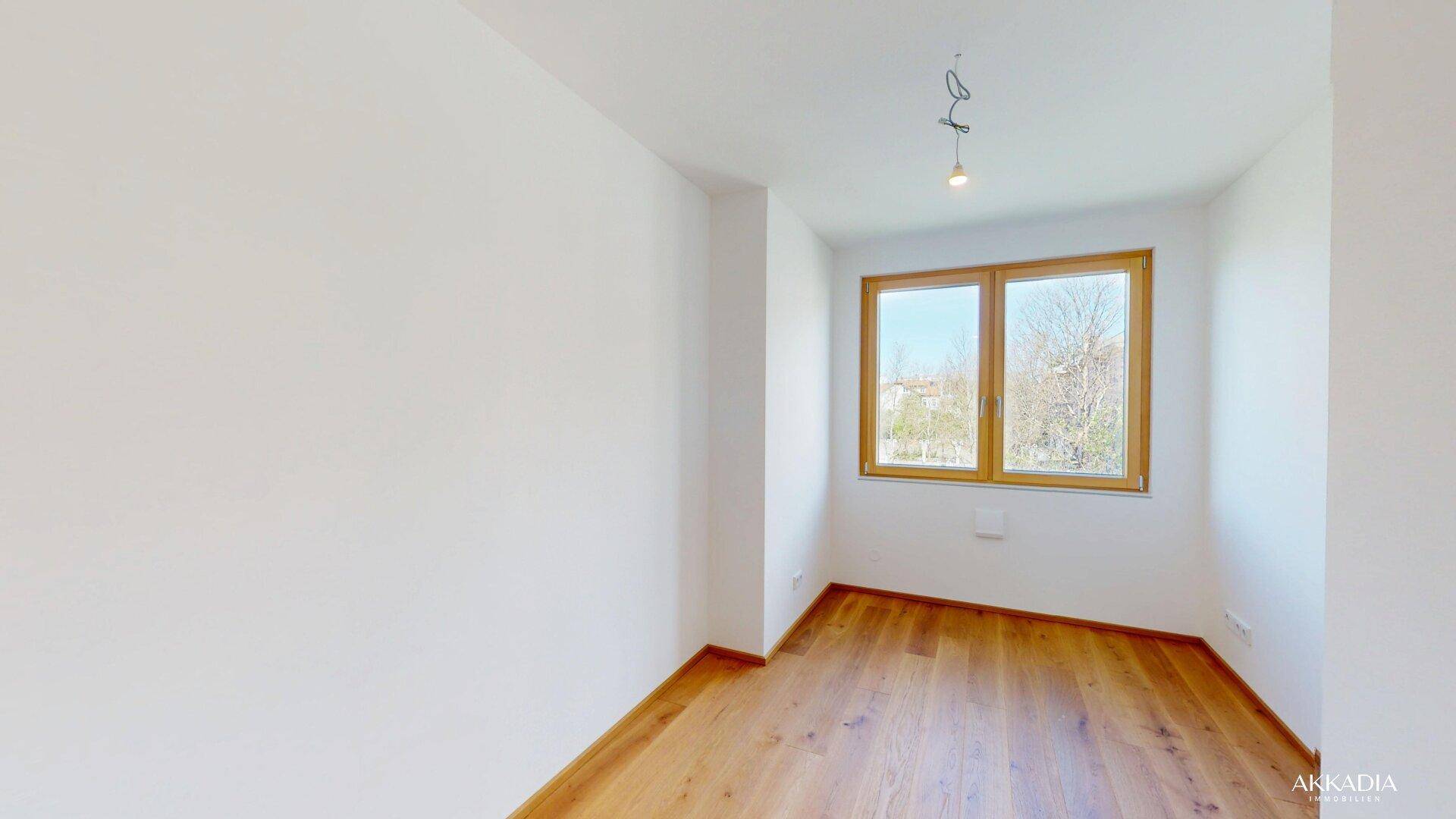 Helles Schlafzimmer mit Holzboden, weißen Wänden und einem großen Fenster.
