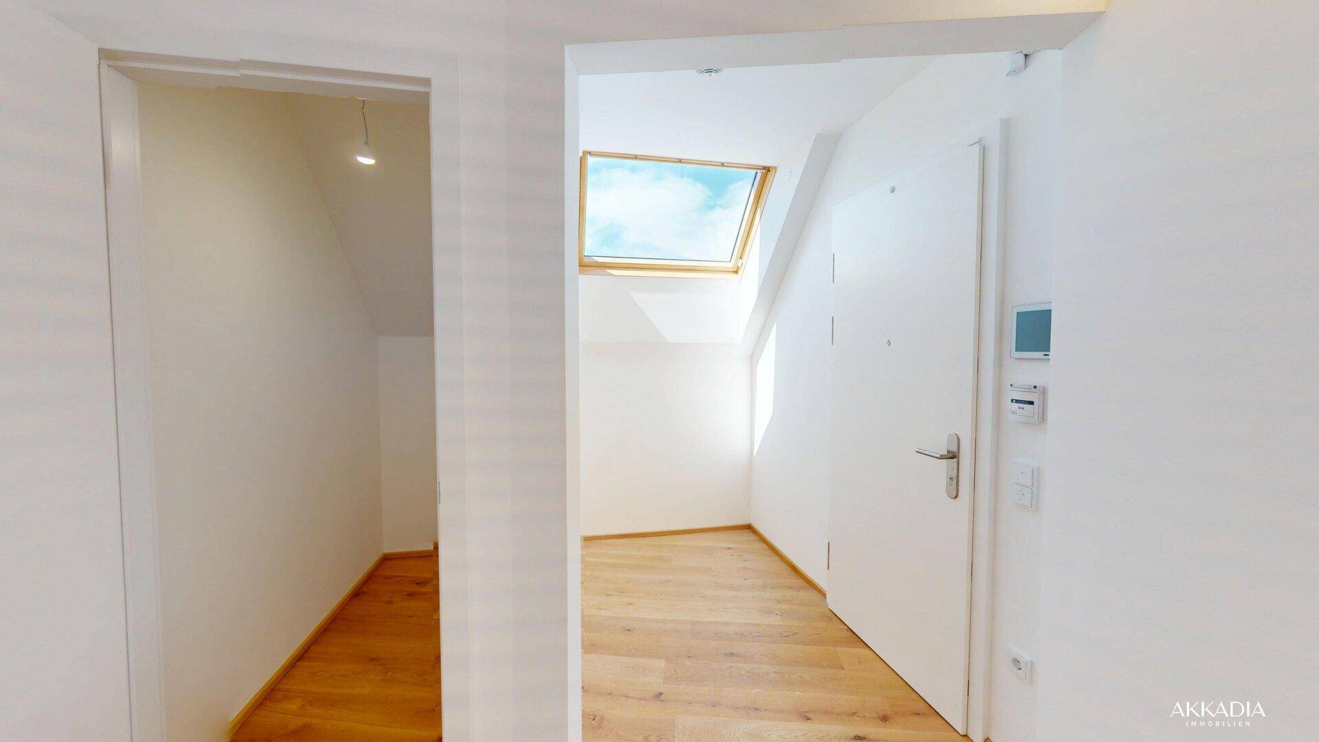 Heller Eingangsbereich mit Holzboden, weißen Wänden und einem Dachfenster.