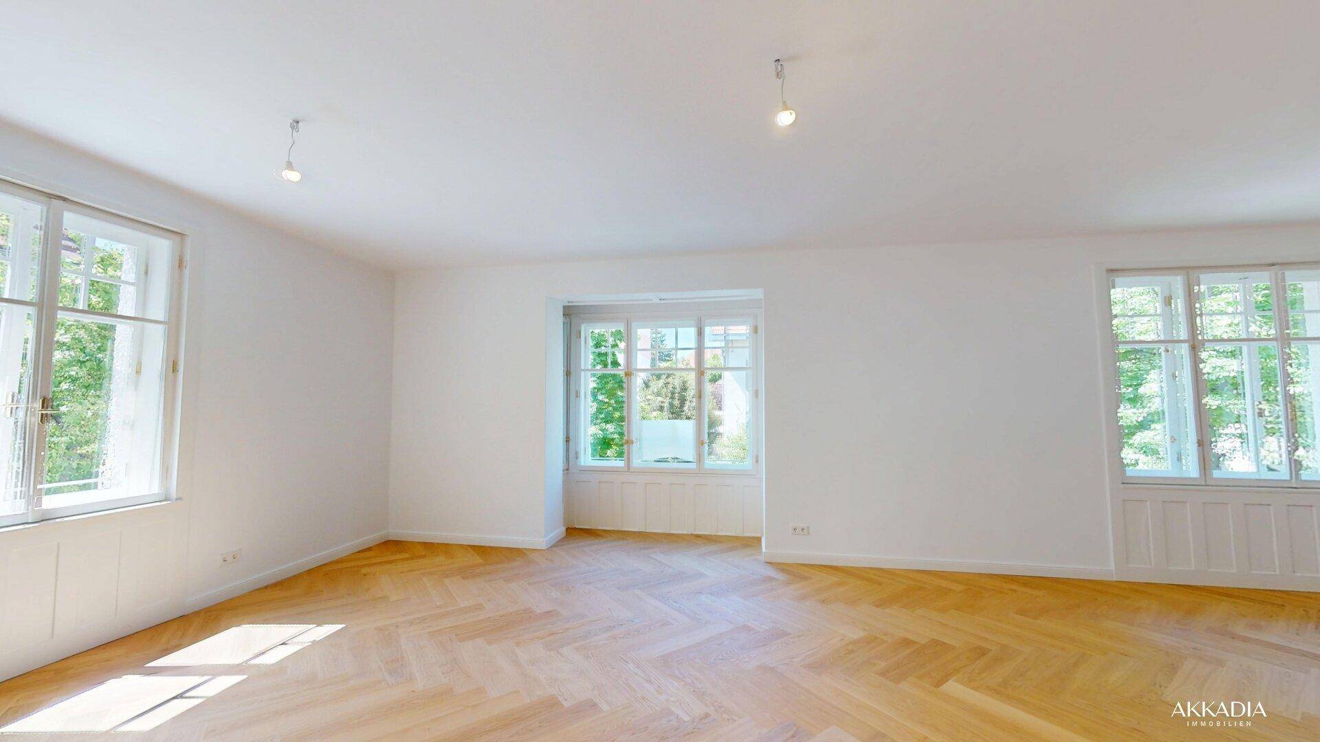 Großes, helles Zimmer mit Fischgrätparkett und mehreren hohen Fenstern.