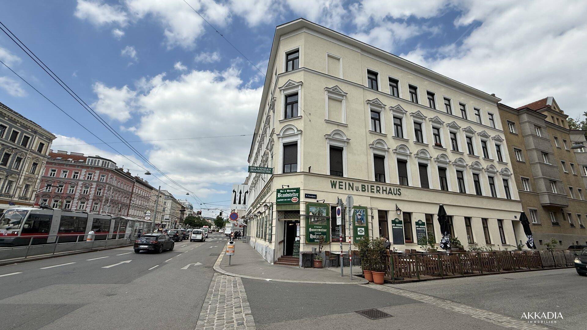 Ein Eckgebäude mit einem Wein- und Bierhaus im Erdgeschoss, umgeben von einer belebten Straße.