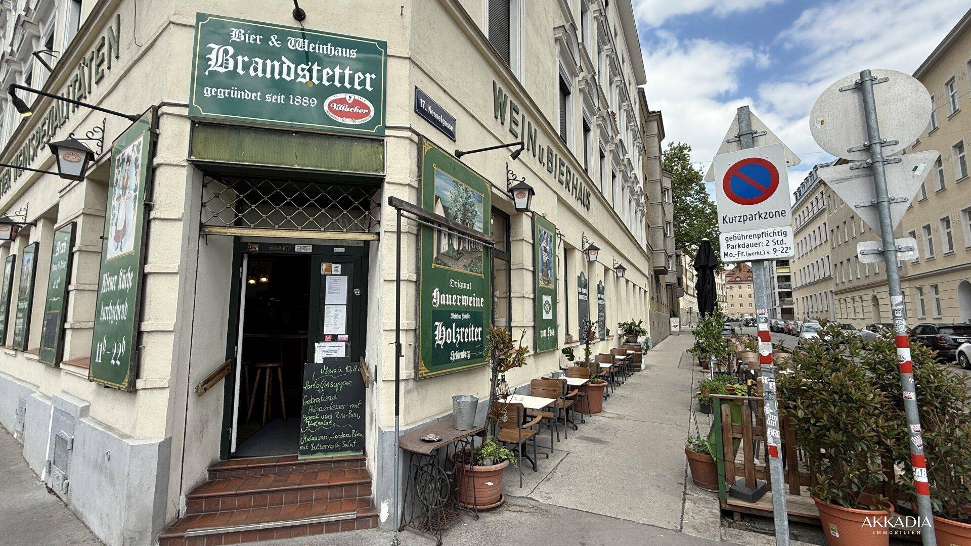 Die Ecke eines traditionellen Wein- und Bierhauses mit Außenterrasse und Straßenschildern.