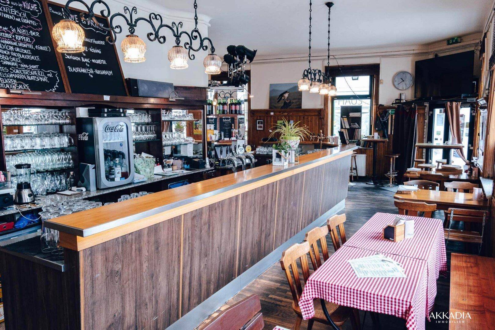 Eine traditionelle Bar mit Holzelementen, Zapfanlage und Tischen mit karierten Tischdecken.