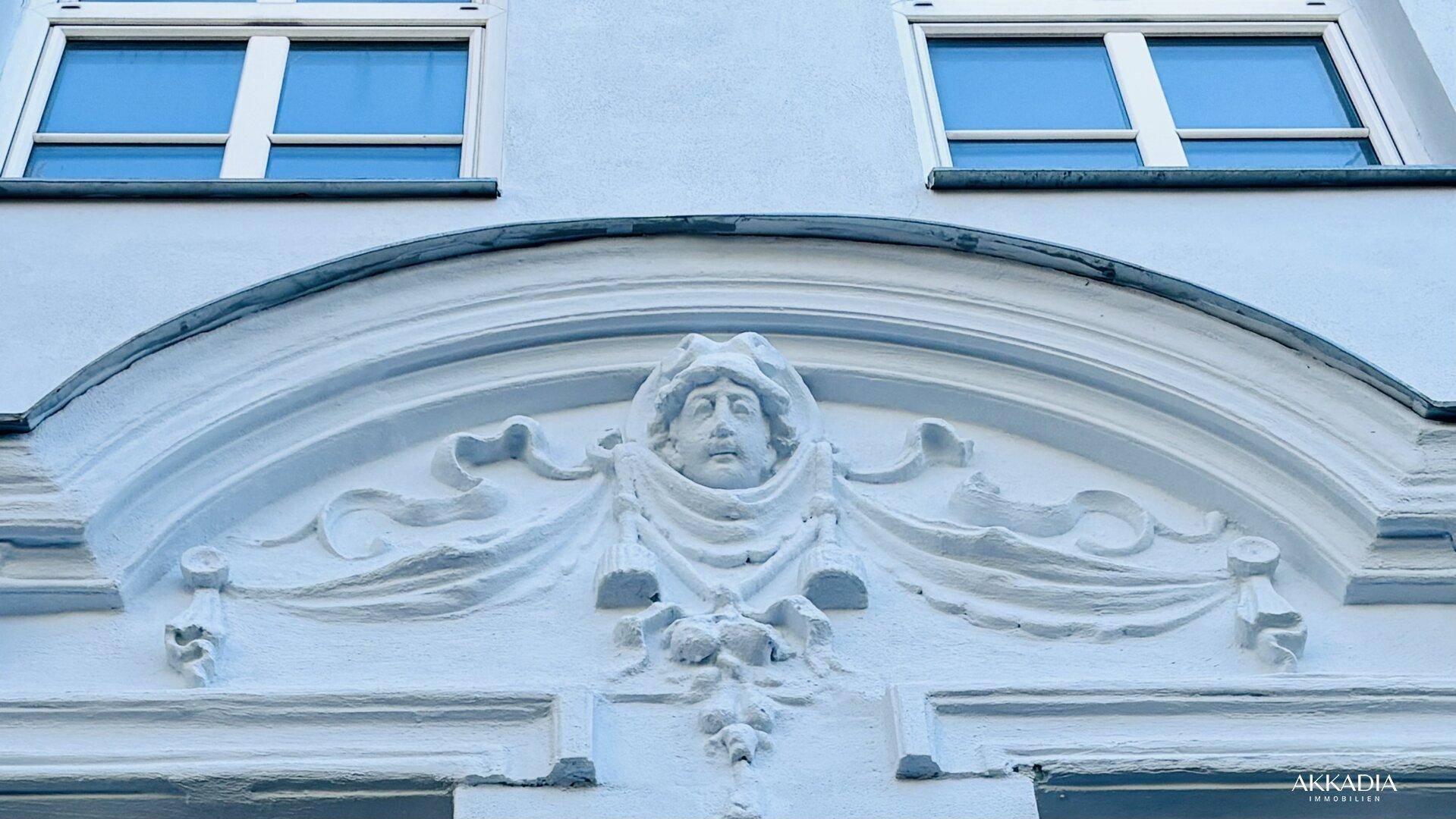 Detail der historischen Fassade mit kunstvoller Stuckverzierung über den Fenstern.