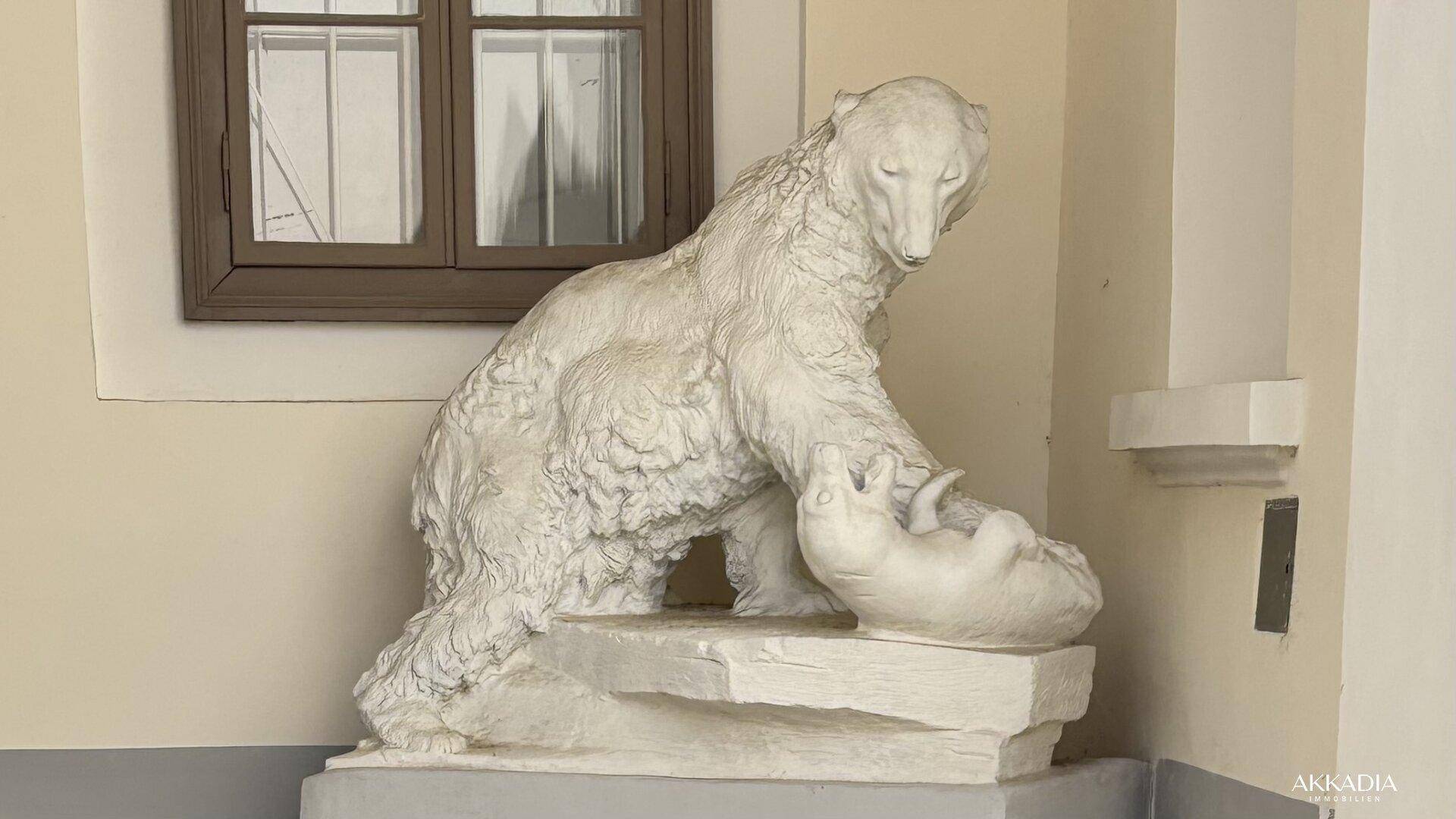 Skulptur eines Eisbären mit Jungtier in einer Nische, beleuchtet von einem Fenster.