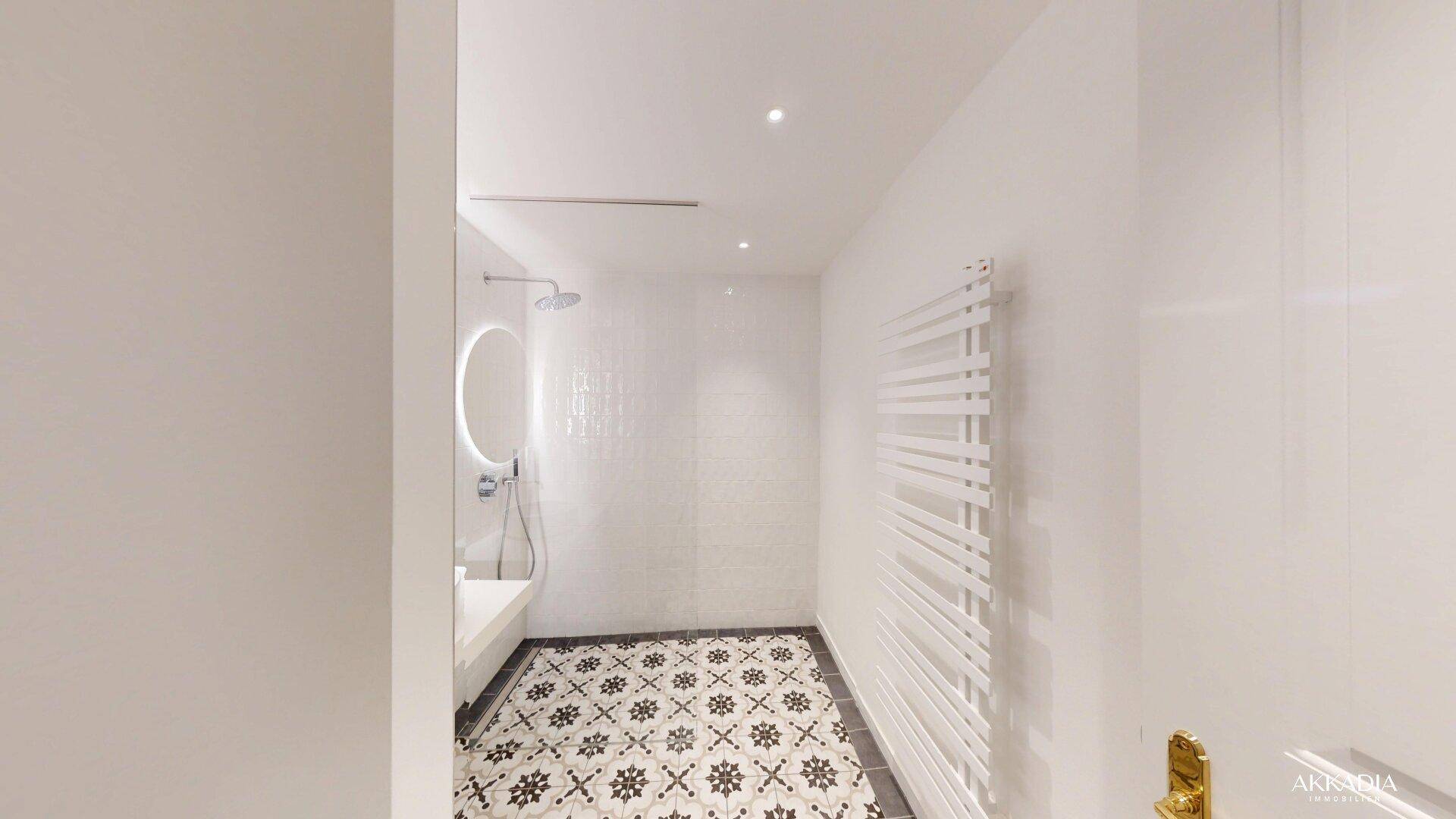 Modernes Badezimmer mit gemusterten Bodenfliesen, begehbarer Dusche und Handtuchheizkörper.
