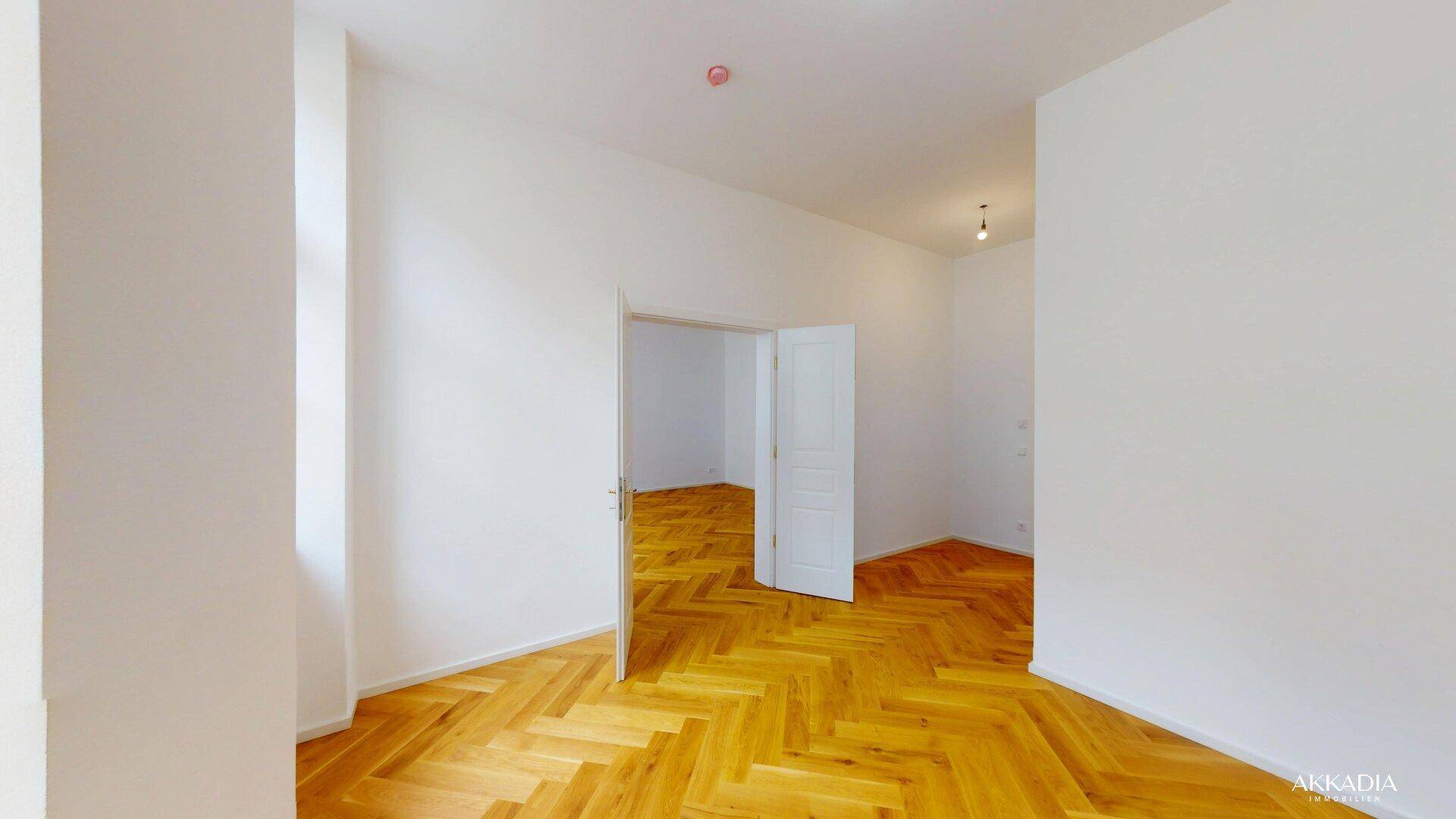 Geräumiges Zimmer mit hellem Fischgrätparkett und hohen Decken, bietet vielseitige Nutzungsmöglichkeiten.
