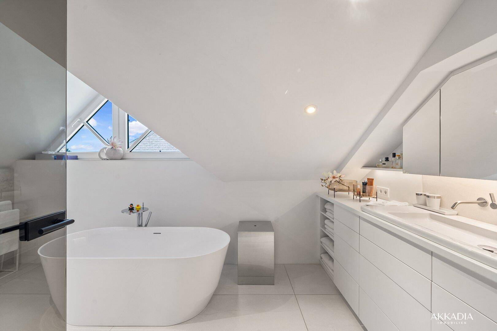 Modernes Badezimmer im Dachgeschoss mit freistehender Badewanne, Doppelwaschbecken und Dachfenster.
