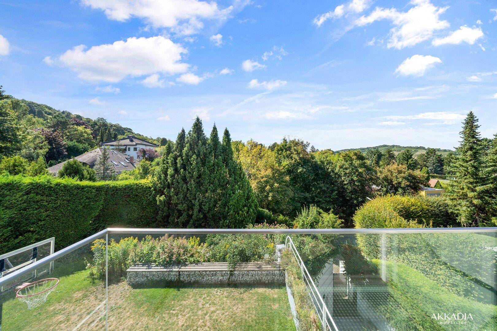Weitläufiger Blick ins Grüne von der oberen Terrasse mit viel Baumbestand.