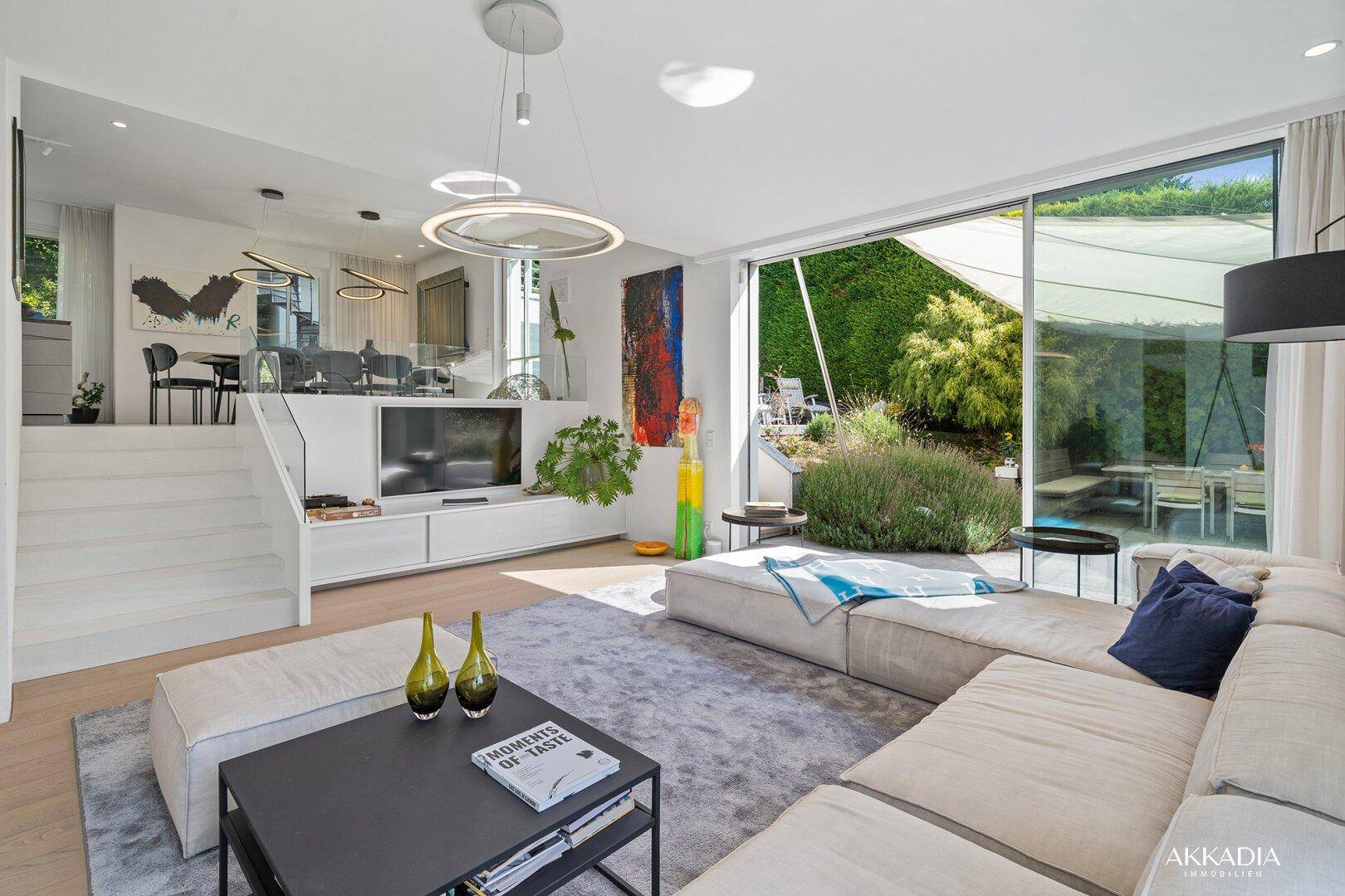 Lichtdurchflutetes Wohnzimmer mit großen Schiebetüren zum Garten und moderner Einrichtung.