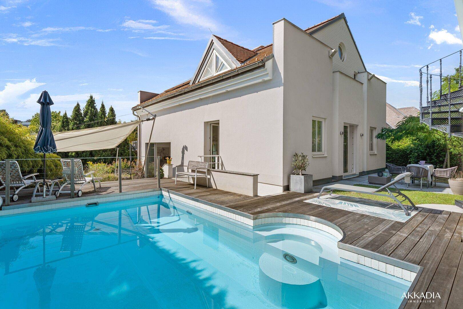 Hausfassade mit Pool, Holzdeck und sonnigem Außenbereich, ideal zum Entspannen.