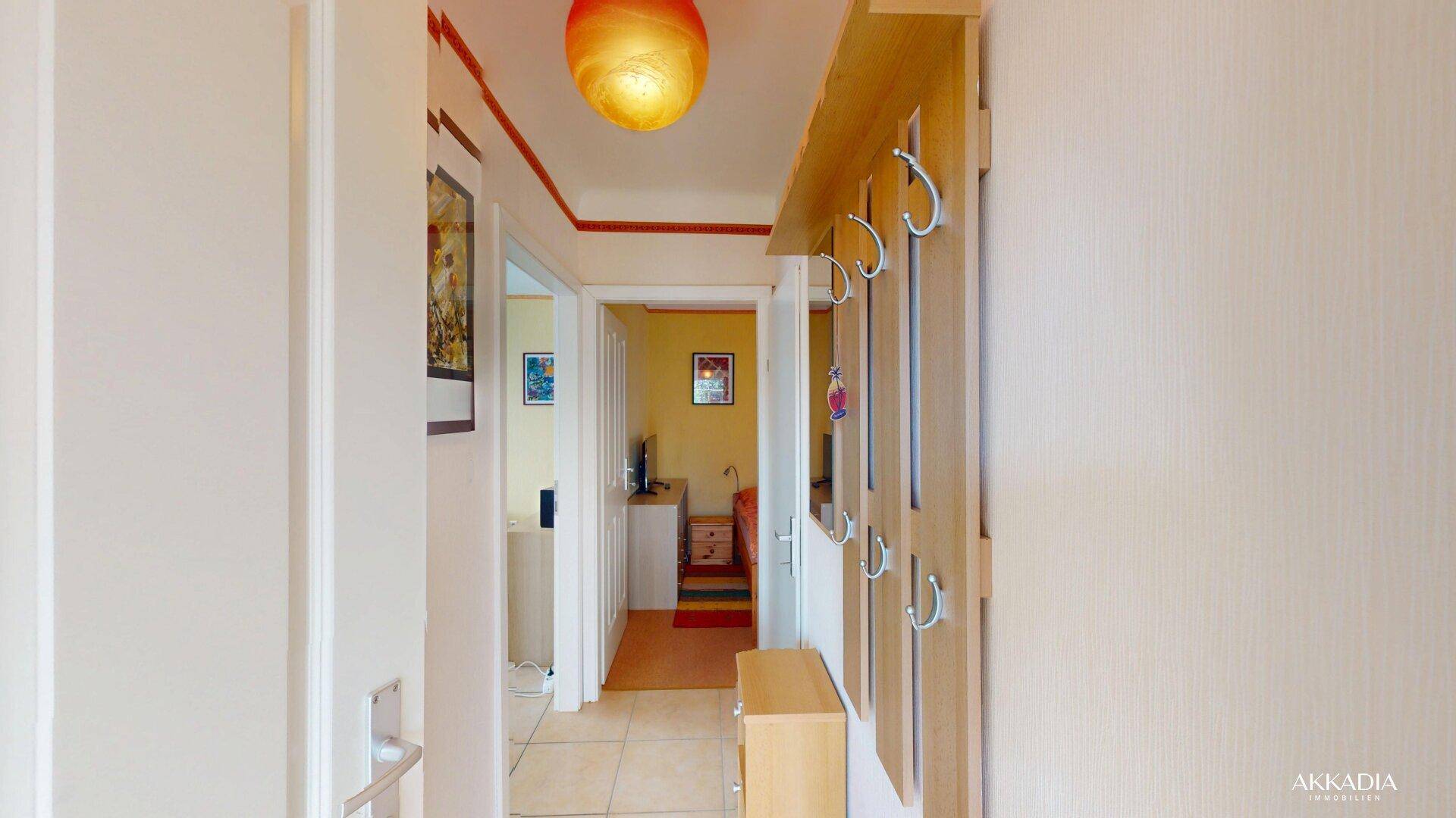 Flur mit heller Wandfarbe, Garderobe und Blick in angrenzende Wohnbereiche.
