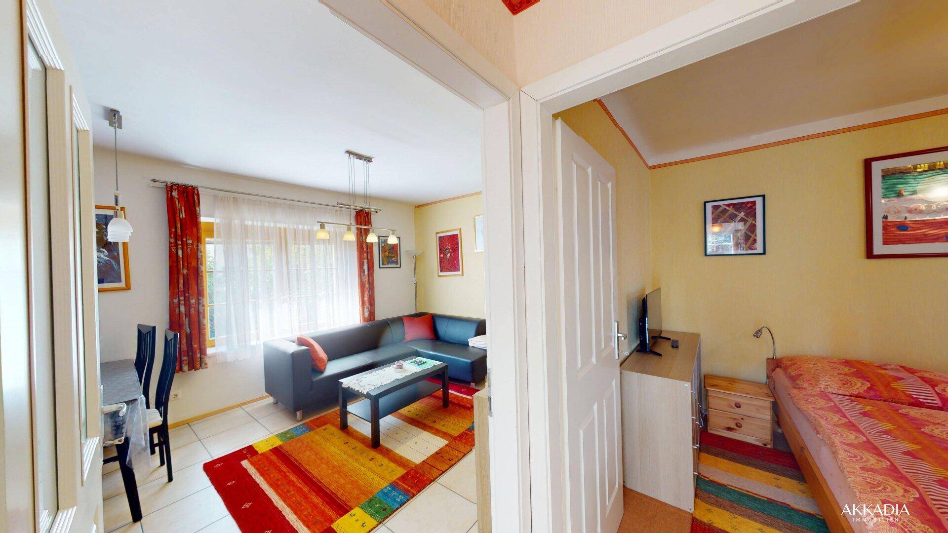 Offener Wohnbereich mit Sofa, Esstisch und Zugang zu einem weiteren Zimmer.