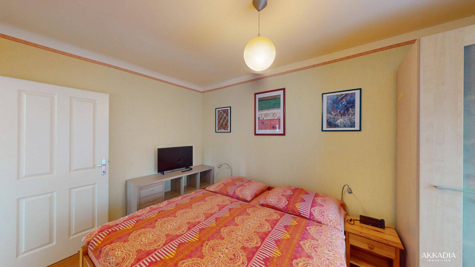 Schlafzimmer mit Doppelbett, Nachttischen und heller Wandgestaltung.