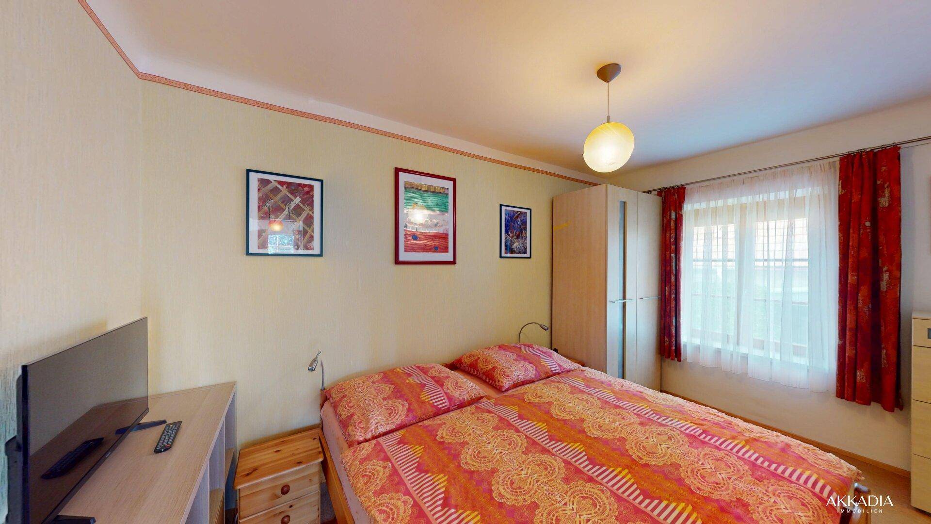 Gemütliches Schlafzimmer mit Doppelbett, Kleiderschrank und Fenster.