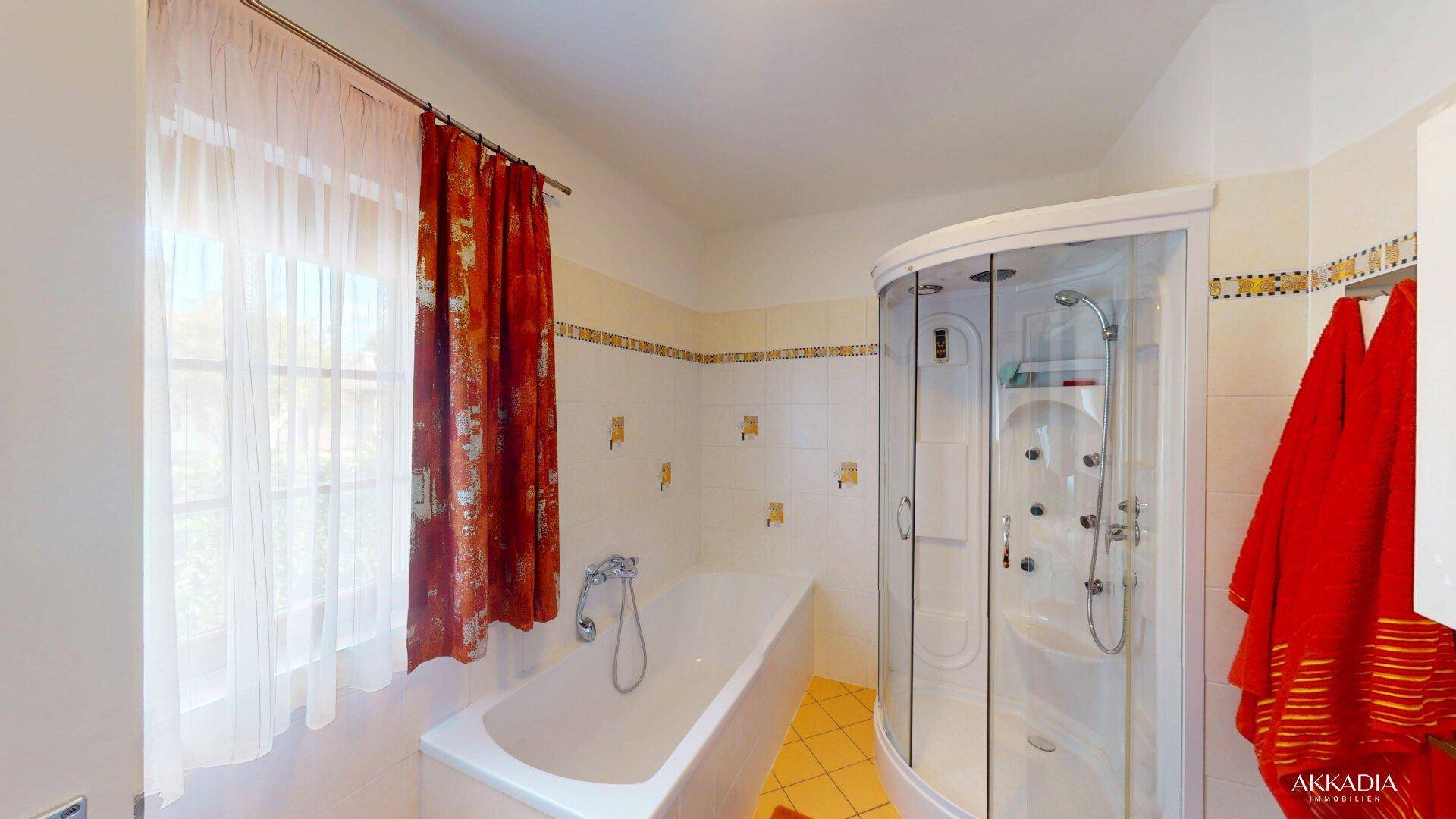 Helles Badezimmer mit Badewanne, Duschkabine und Fenster.