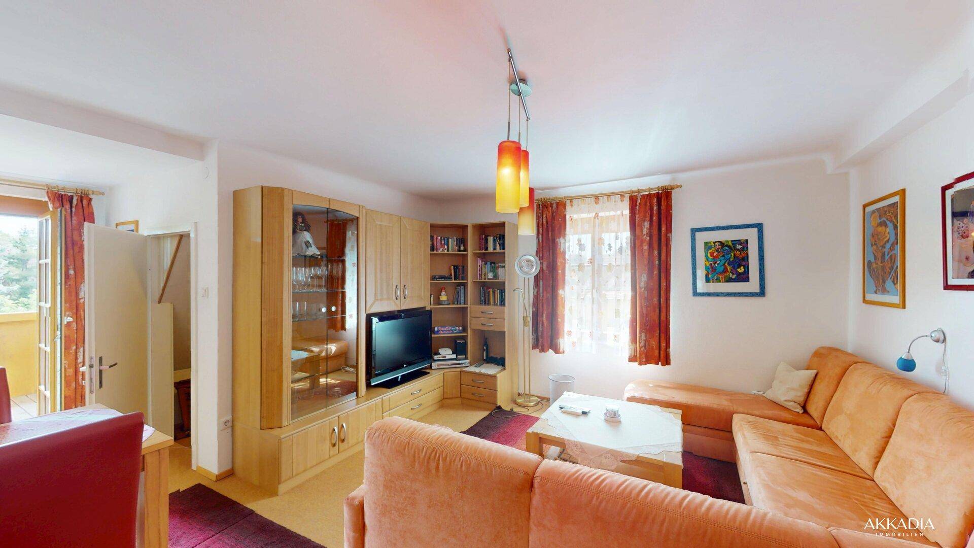 Gemütliches Wohnzimmer mit Ecksofa, Wohnwand und Zugang zum Balkon.