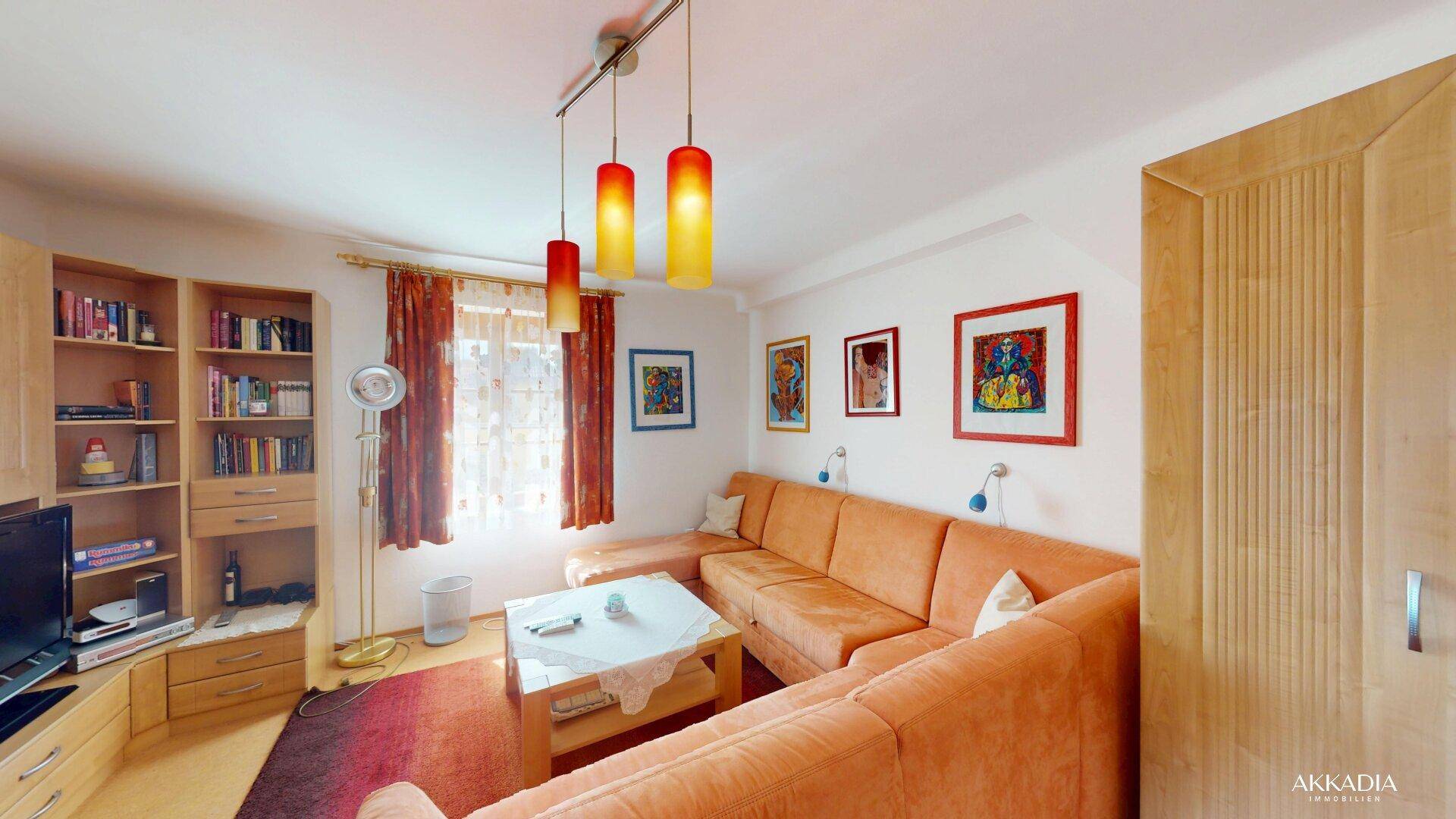 Helles Wohnzimmer mit bequemer Eckcouch, Holzschrankwand und Blick nach draußen durch die Fenster.