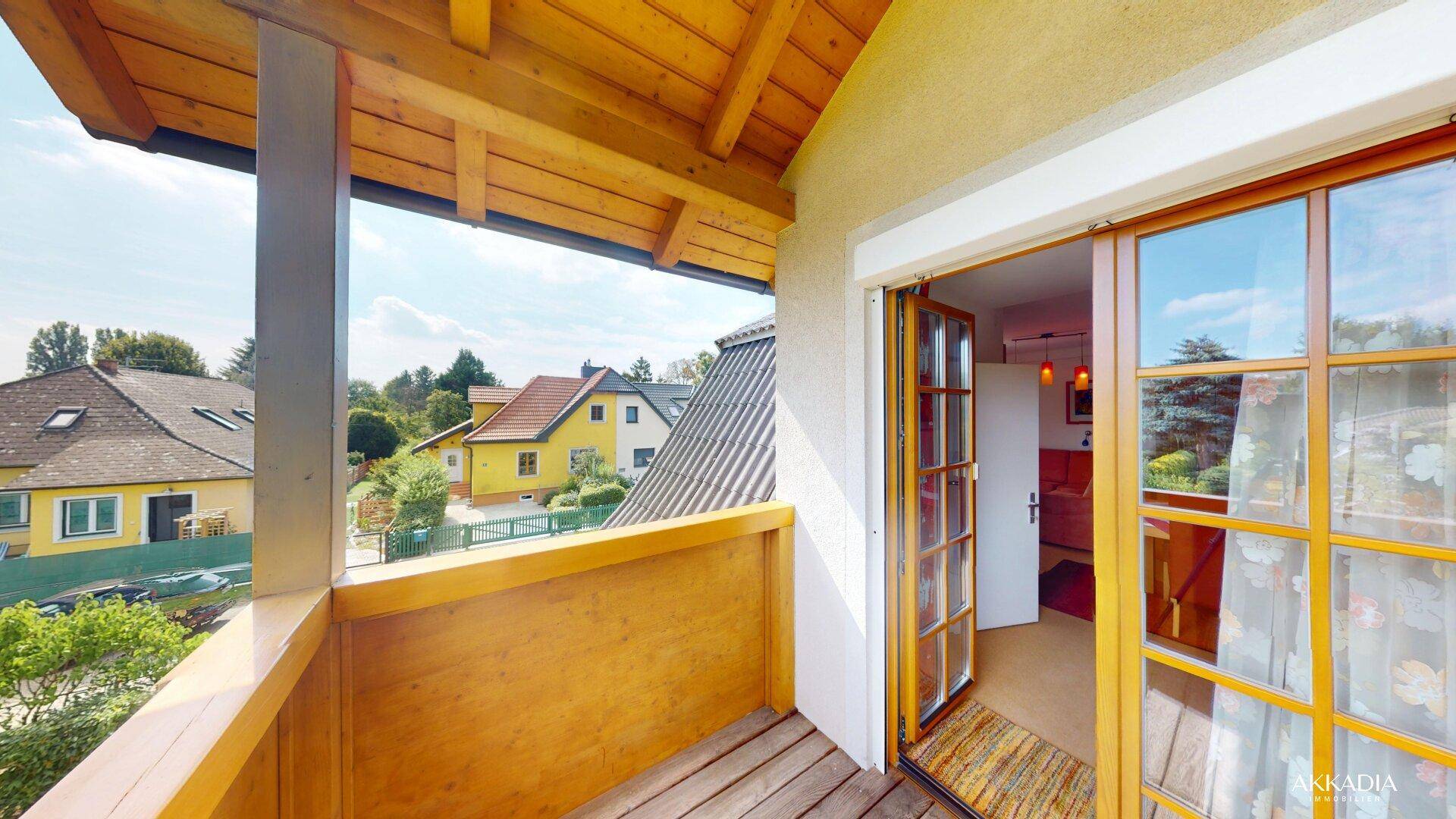 Balkon mit Holzboden und Zugang zum Innenbereich, bietet einen schönen Ausblick auf die Dächer der Nachbarschaft.