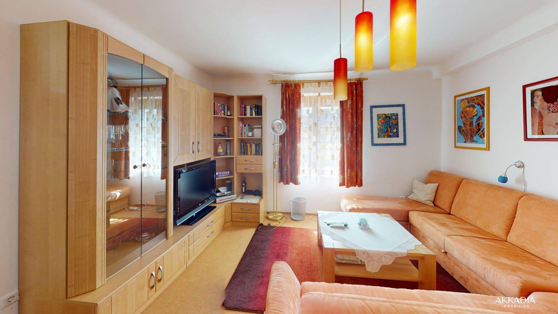 Gemütliches Wohnzimmer mit großer Eckcouch, Holzmöbeln und farbigen Hängelampen, ideal zum Entspannen.