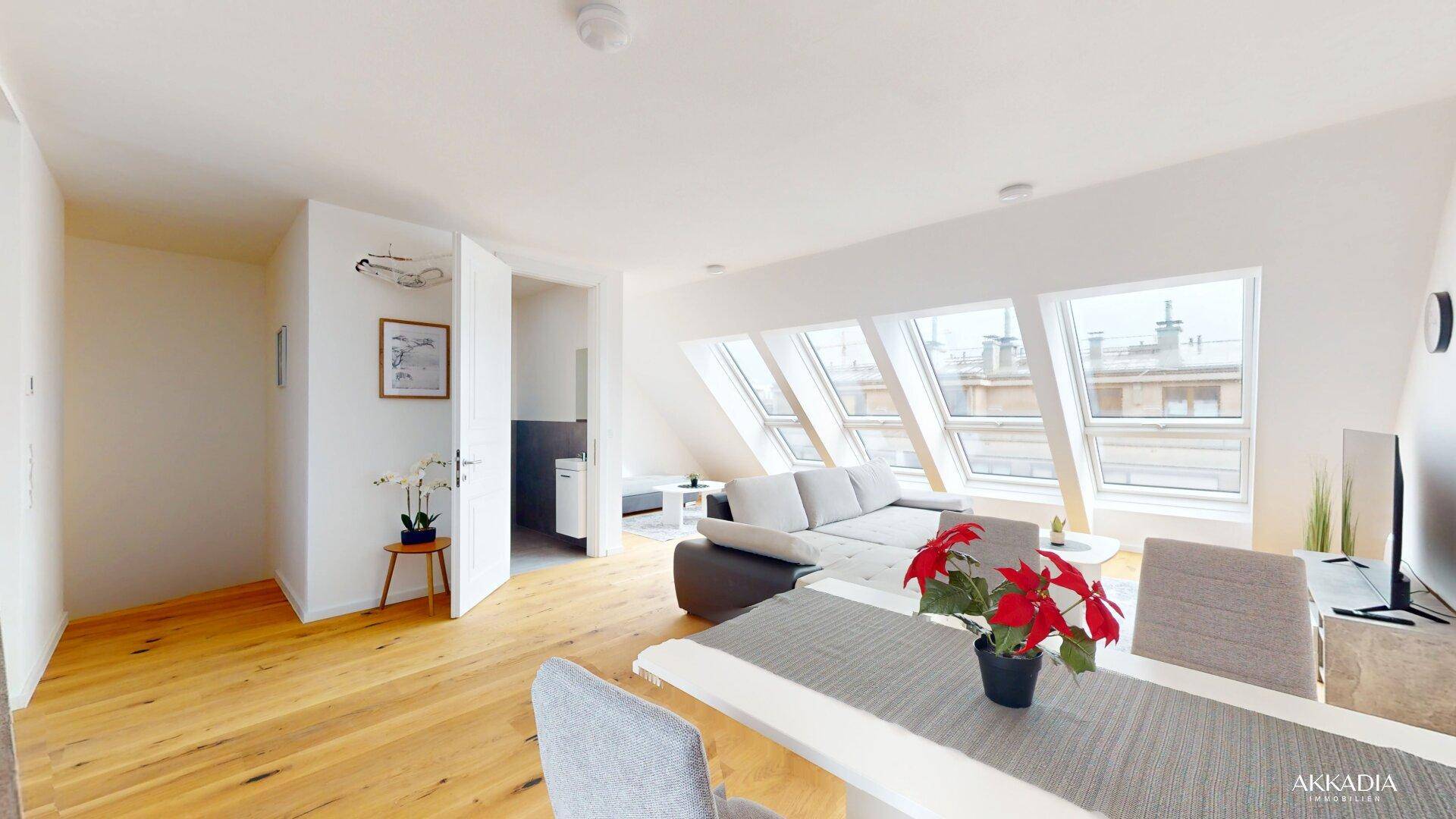 Geräumiges Wohn-Esszimmer mit Holzboden, Dachfenstern und Zugang zu einem weiteren Raum.