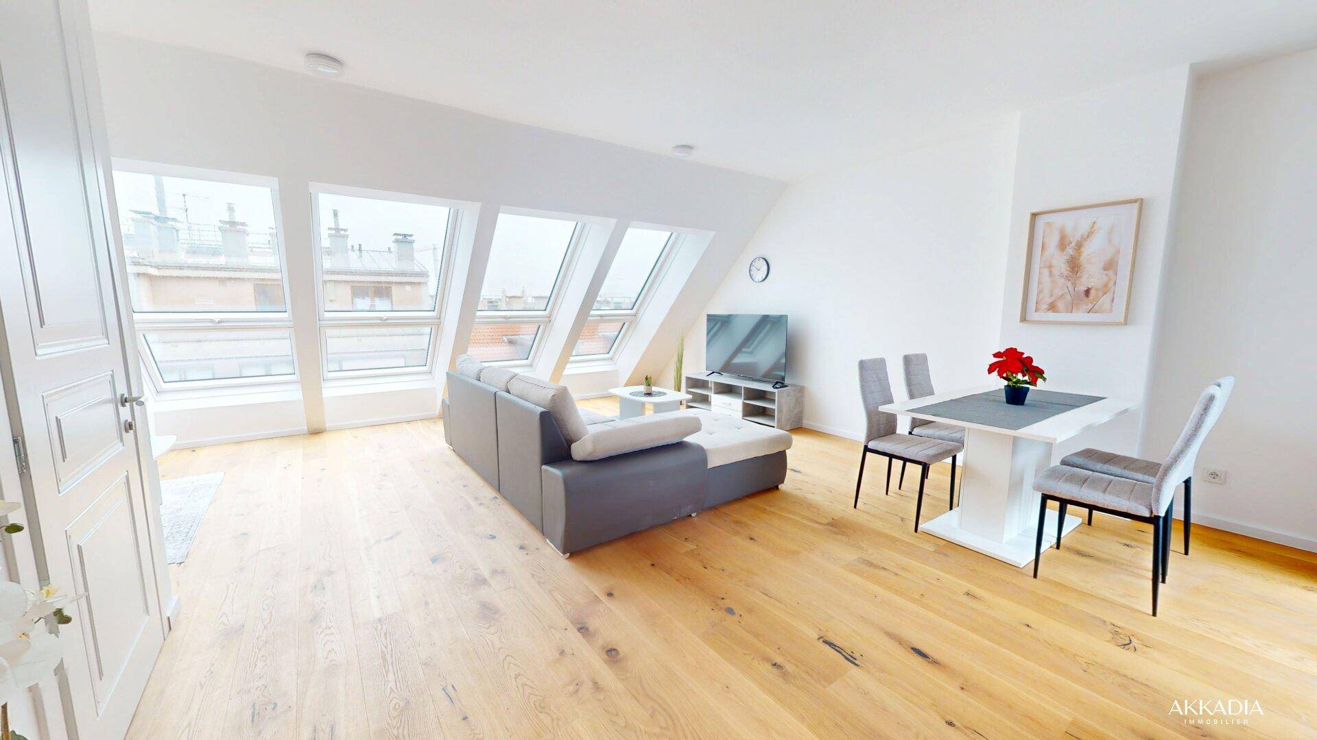 Helles, offenes Wohn-Esszimmer mit Holzboden, Dachschrägen und großen Dachfenstern.