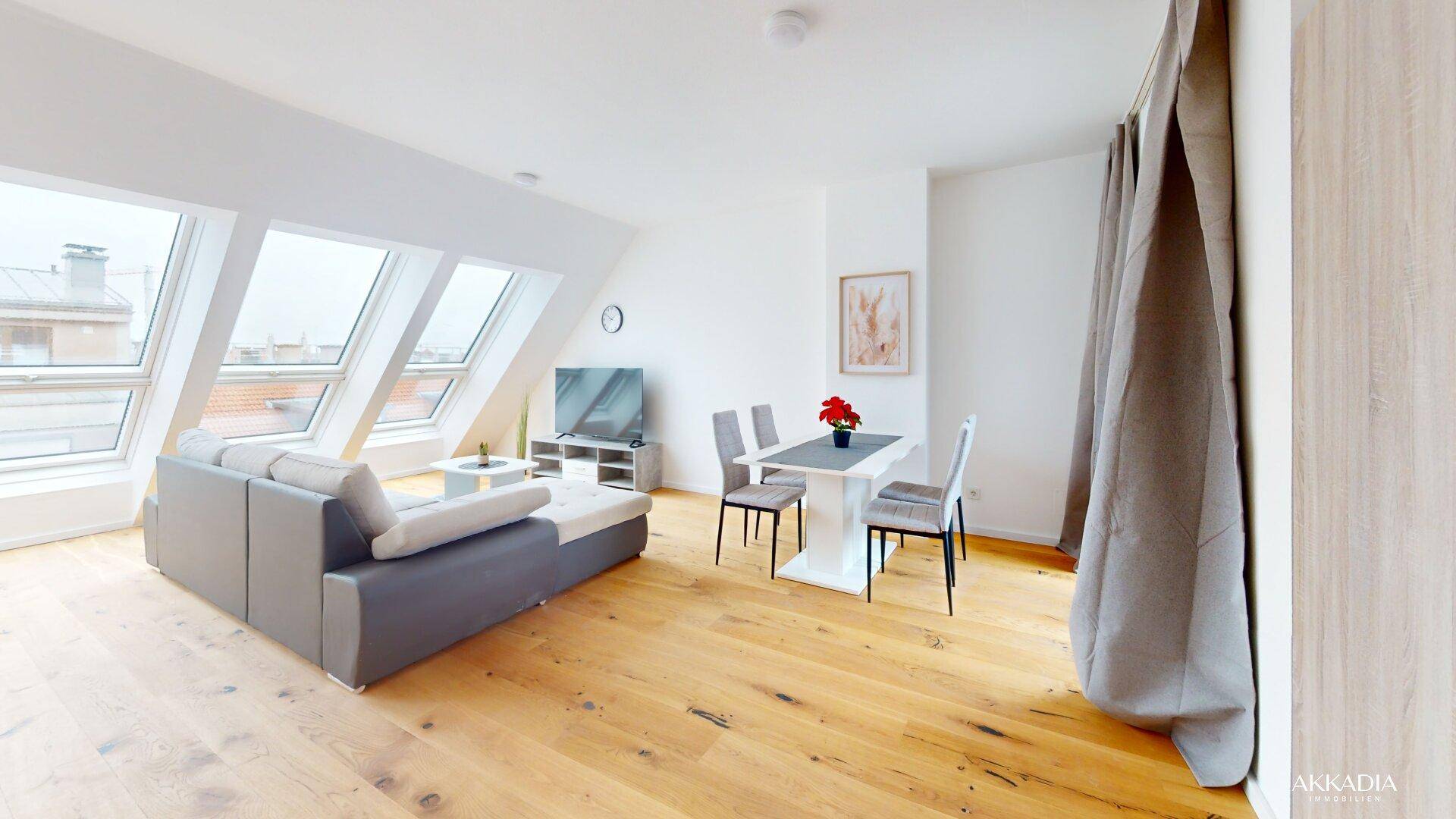 Lichtdurchflutetes Wohn-Esszimmer mit Holzboden, Dachschrägen und großen Dachfenstern.