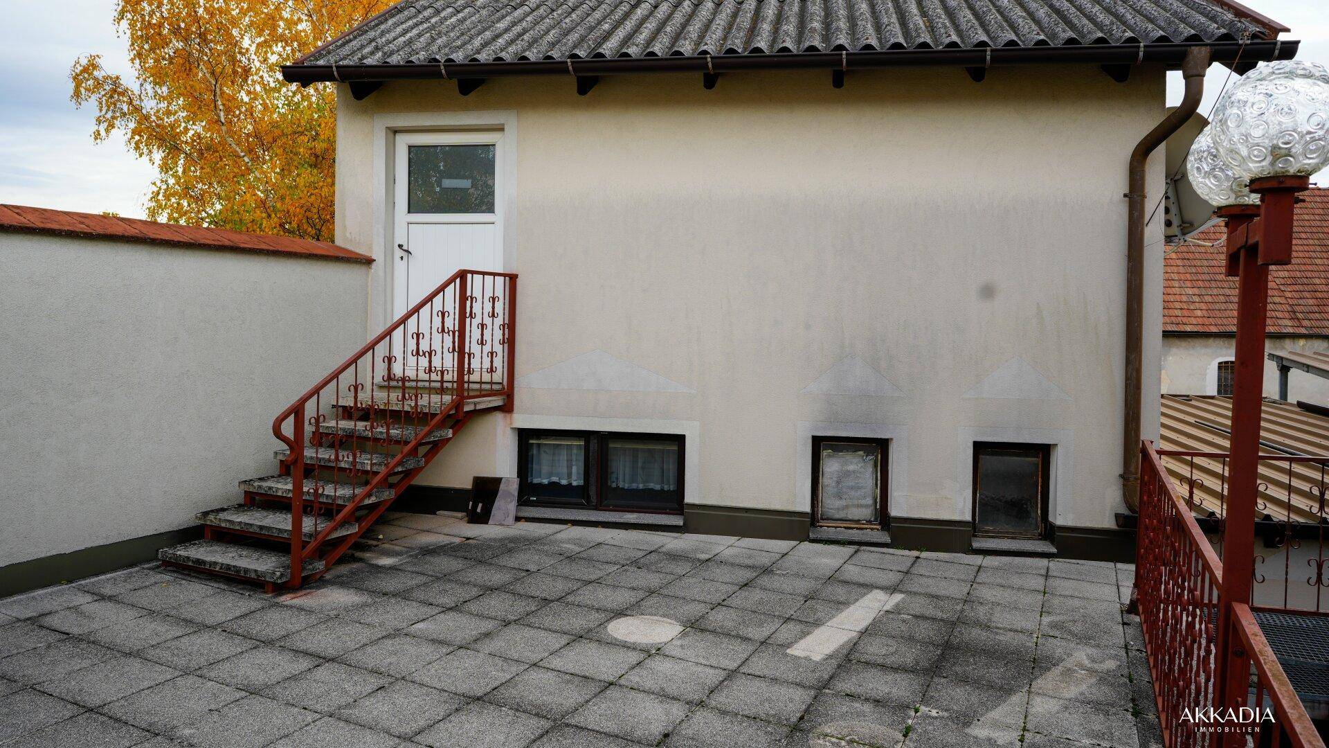 Seitenansicht des Hauses mit Außentreppe, die zur Dachterrasse führt.