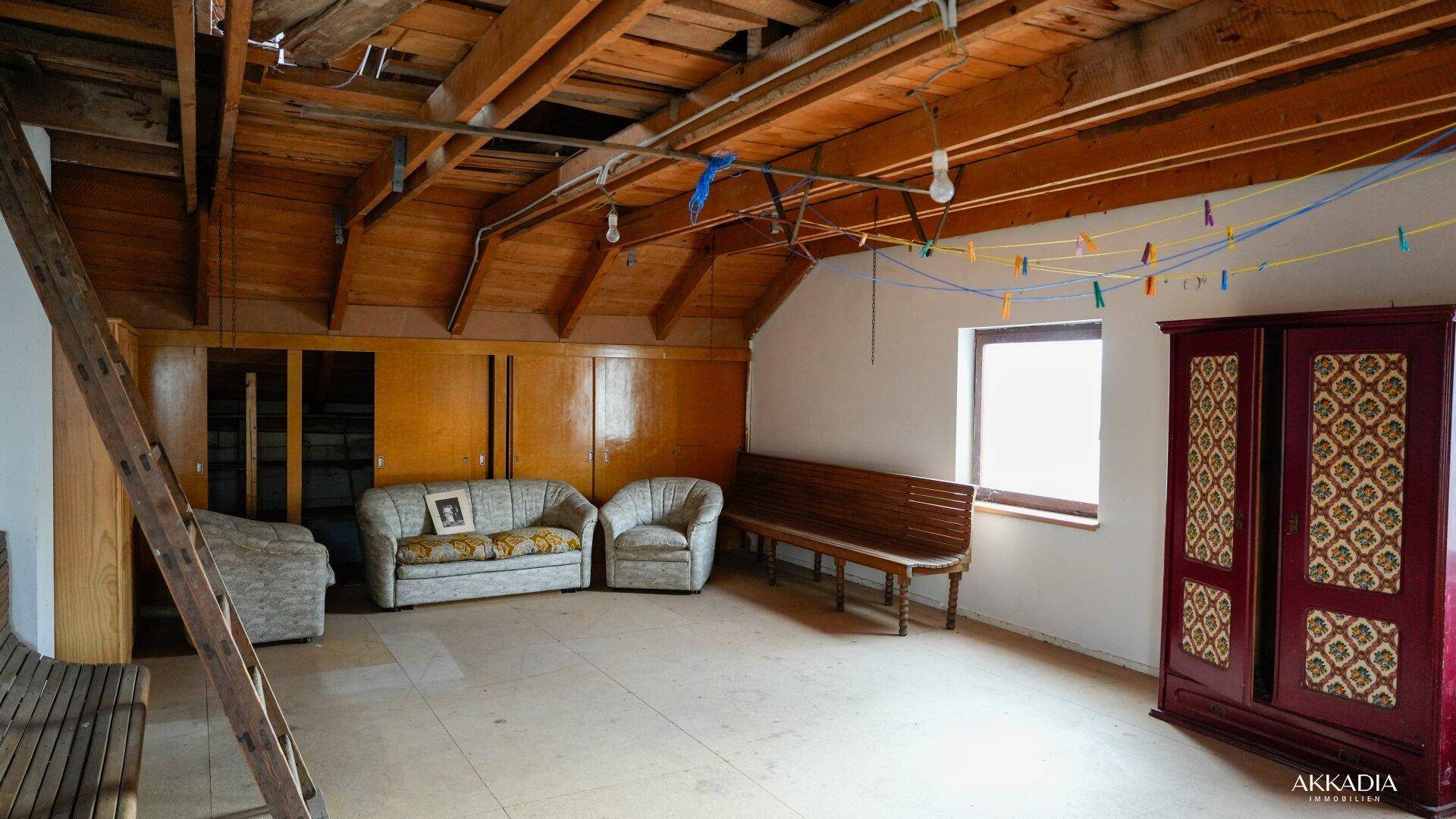 Geräumiger Dachboden mit sichtbaren Holzbalken und Sitzgelegenheiten, ideal als Stauraum.