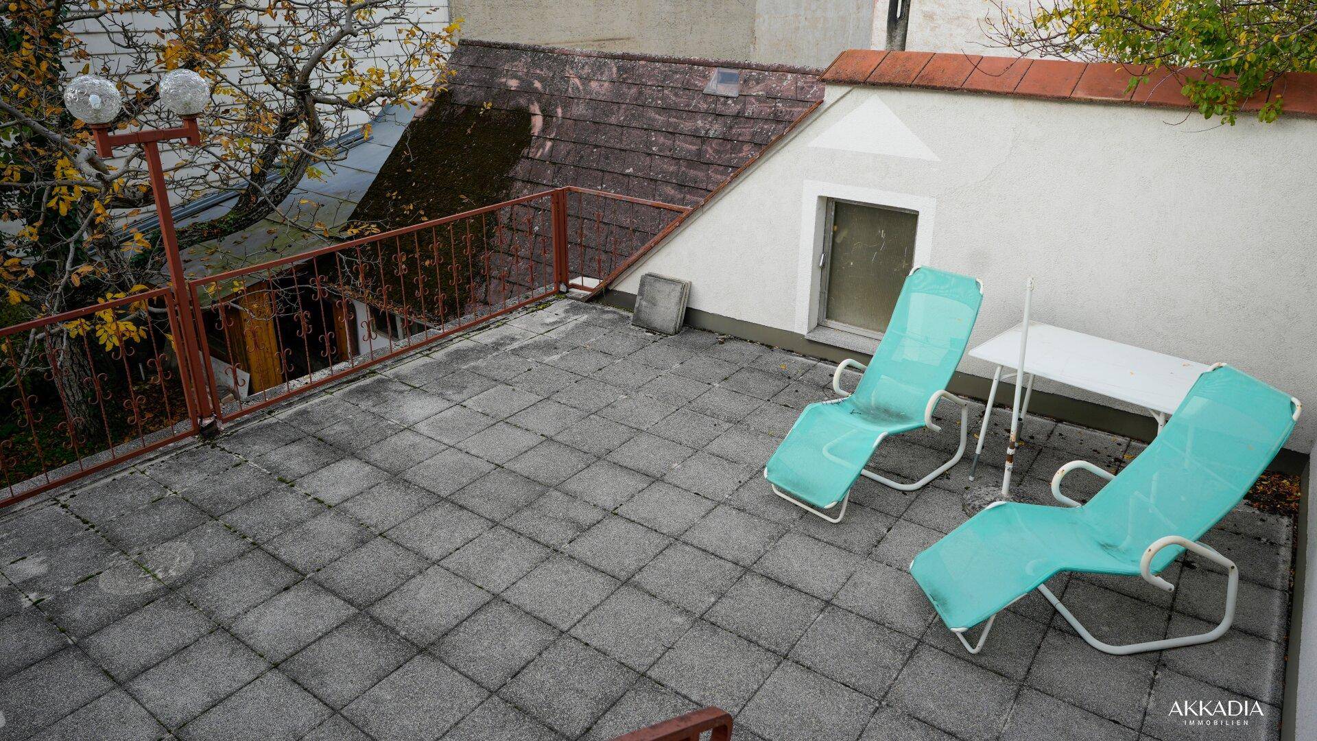 Dachterrasse mit Liegestühlen und Blick auf die umliegenden Gebäude und Bäume.