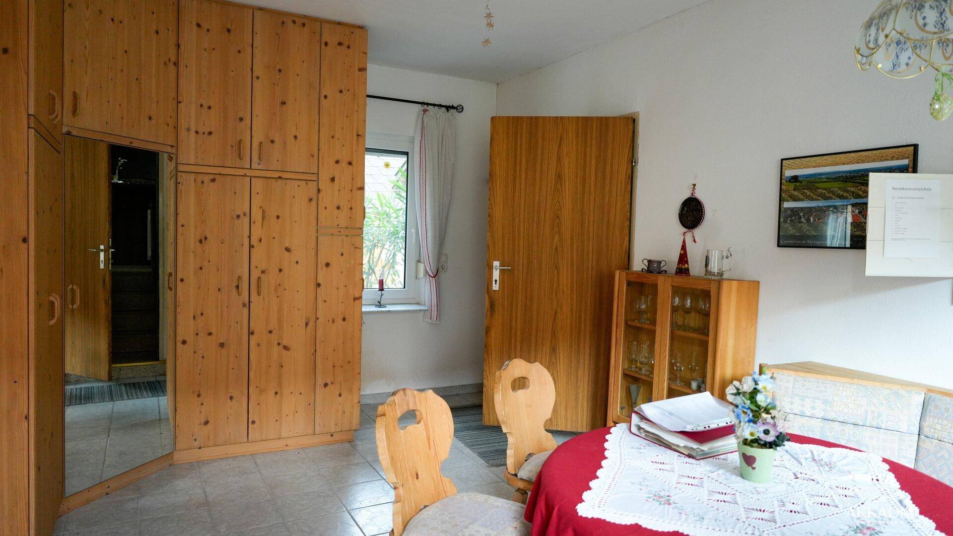 Essbereich mit rustikalen Holzmöbeln, Fliesenboden und Blick ins Grüne.