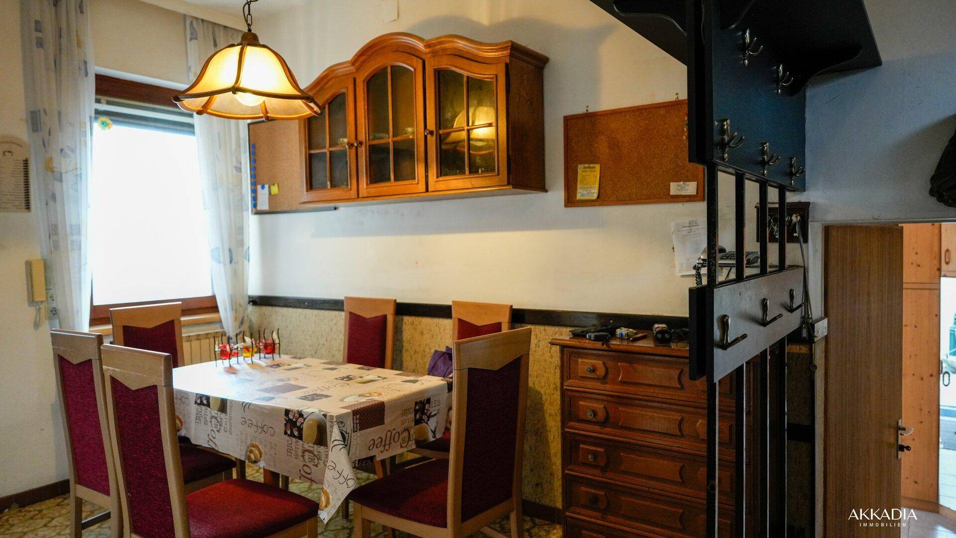 Traditioneller Essbereich mit Holztisch, Stühlen und einem Hängeschrank.